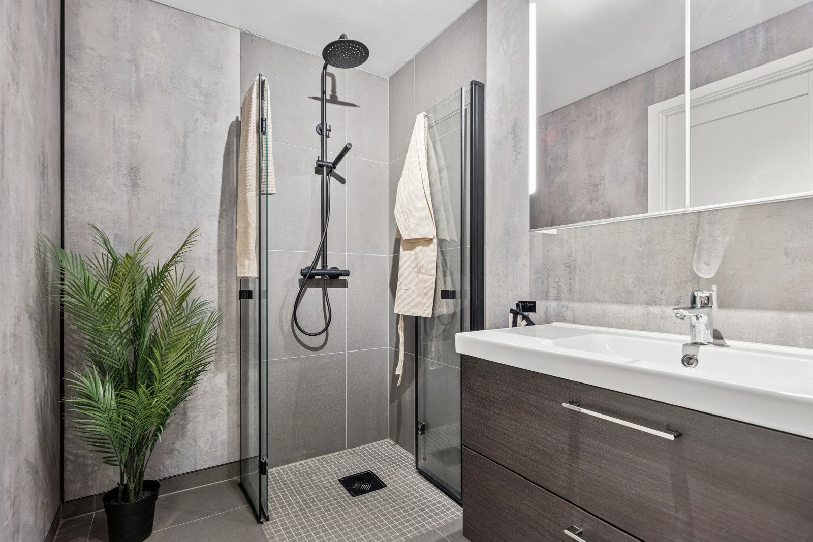 Videre inn i gangen til venstre har man boligens baderom. Baderommet ble pusset opp høsten 2023 og er pent utført med lune tidløse fliser på gulv med varmekabler og pene baderomsplater på vegger. Galleribilde