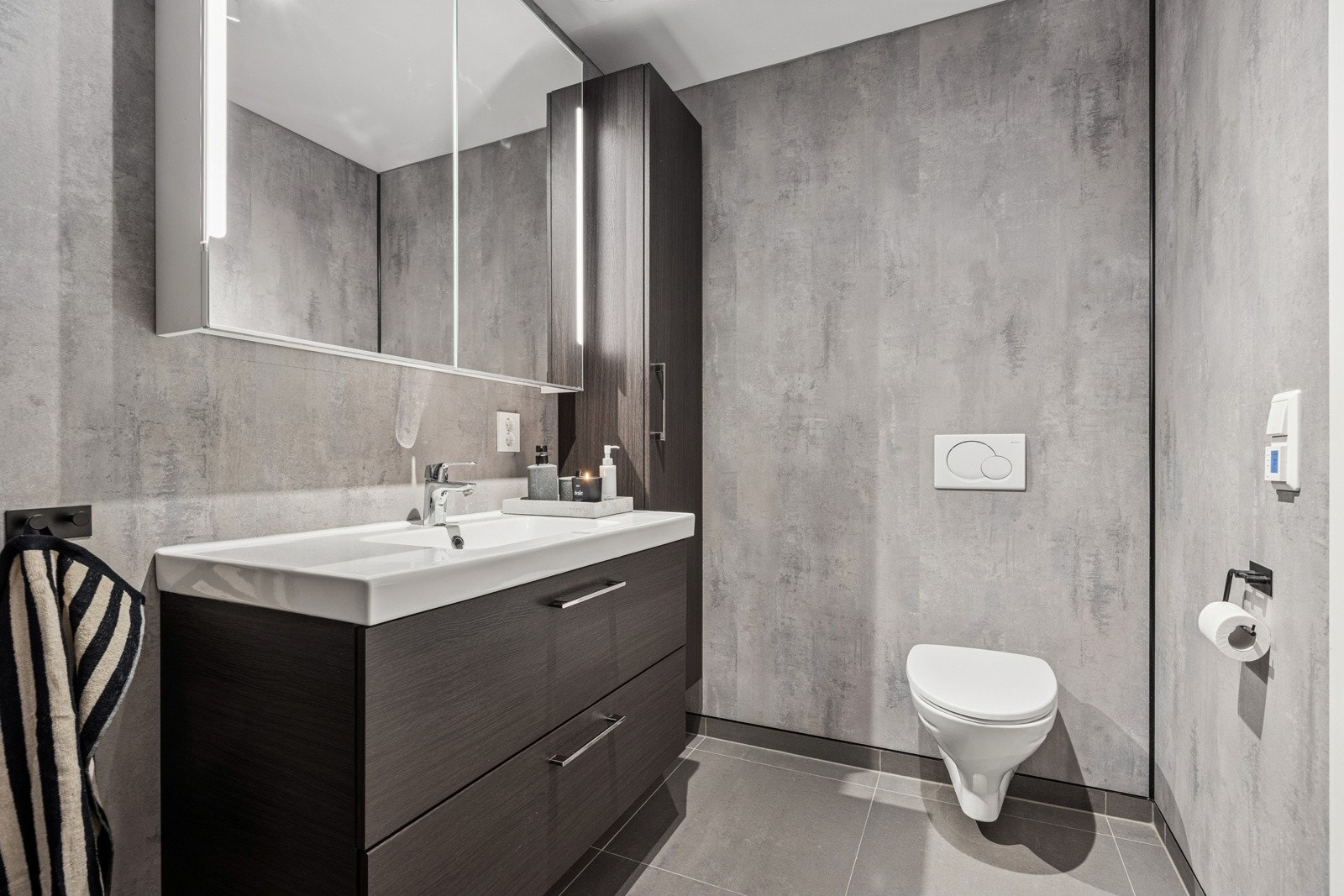 Baderommet har en pen innredning med god oppbevaringsplass, stort speil med innebygd belysning, vegghengt toalett og et meget pent dusjhjørne med både fossefallsdusj og håndholdt dusj. Galleribilde