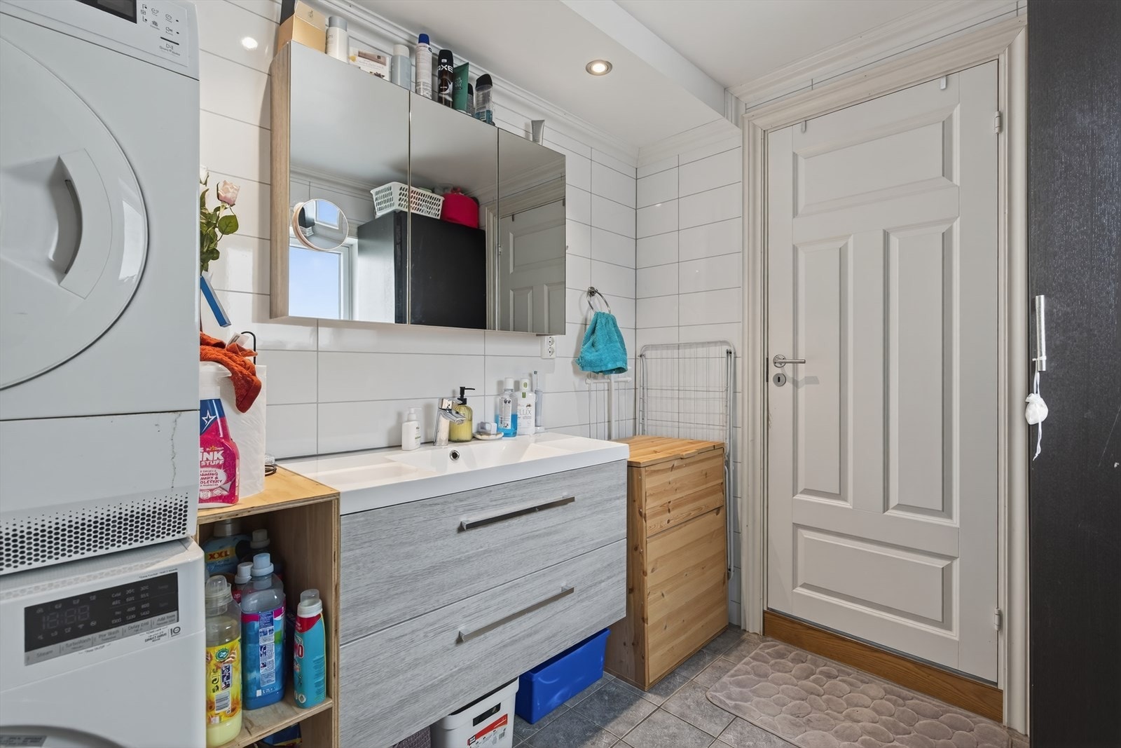 Bad med helstøpt servant i skuffeseksjon, speilskap. Flis på gulv og vegger, malt tak med spotter. Galleribilde