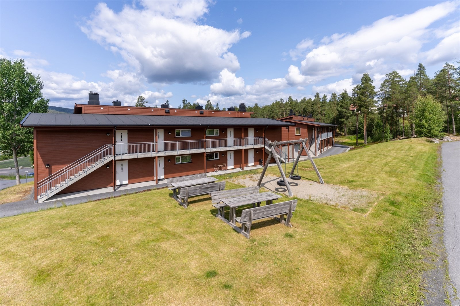 Lett skrånet felles tomt. Opparbeidet med gressplen, beplanting, og asfaltert gårdsplass. Galleribilde