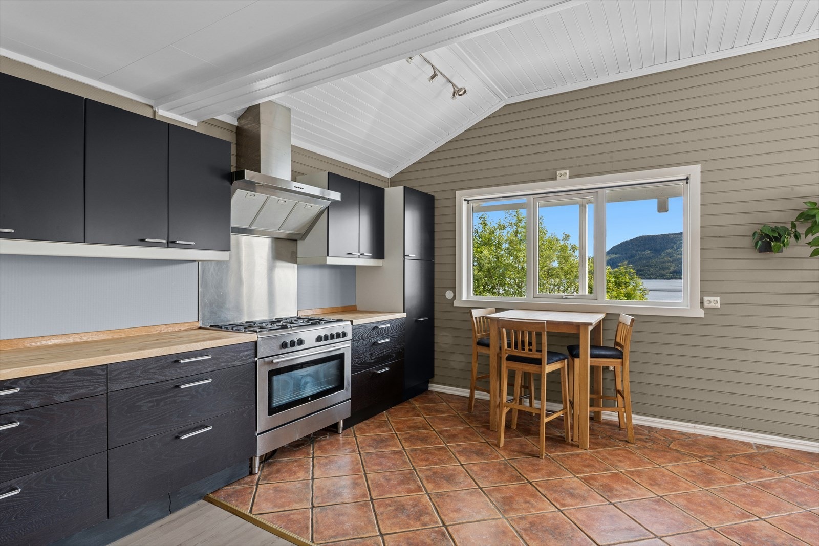 Kjøkkeninnredning av laminerte skrog med laminerte slette fronter, heltre benkeplater med nedfelt oppvaskkum i stål med ett-greps blandebatteri og avrenningsplate. Galleribilde