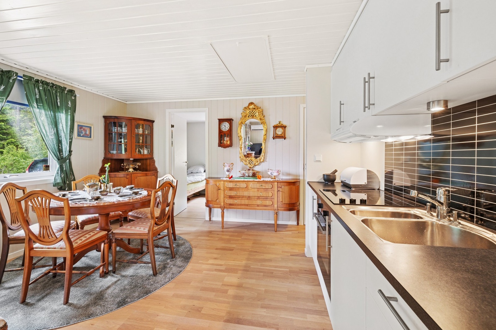 Kjøkkeninnredning med glatte fronter, benkeplater av laminat og nedfelt oppvaskkum med ett-greps armatur. Galleribilde