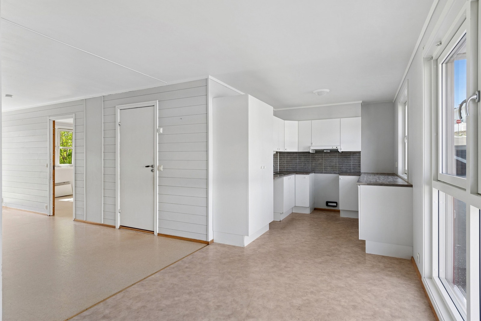 Kjøkkenet har en funksjonell innredning med laminerte skrog, glatte fronter og en laminert benkeplate med kjøkkenkum. Galleribilde