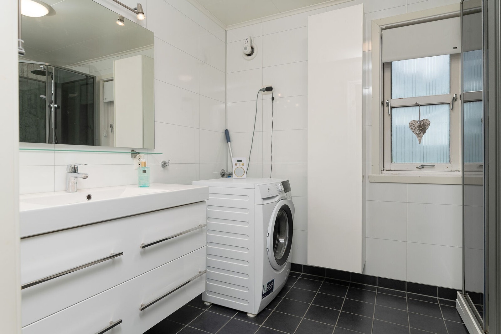 Bad/vaskerom i 1. etasje ble oppusset i 2018. Flislagt gulv med elektrisk gulvvarme og skuffeseksjon med servant. Galleribilde