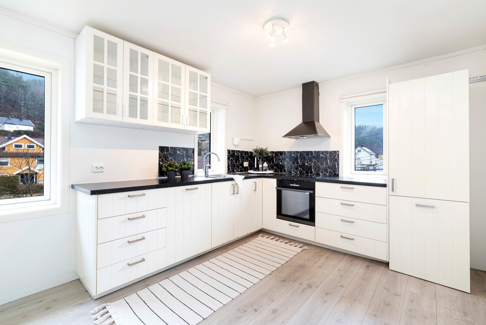 Lyst og stilrent kjøkken med lyse fronter og mørk benkeplate Galleribilde