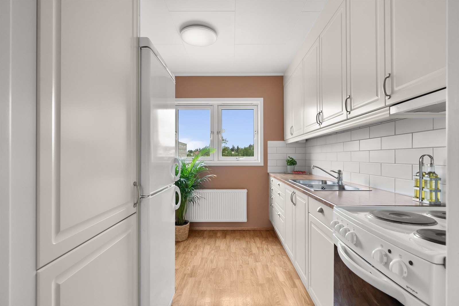 Den takoppbygde innredningen fra Norema har hvite, profilerte fronter, benkebelysning, laminatbenkeplater og nedfelt, dobbel oppvaskkum. Galleribilde