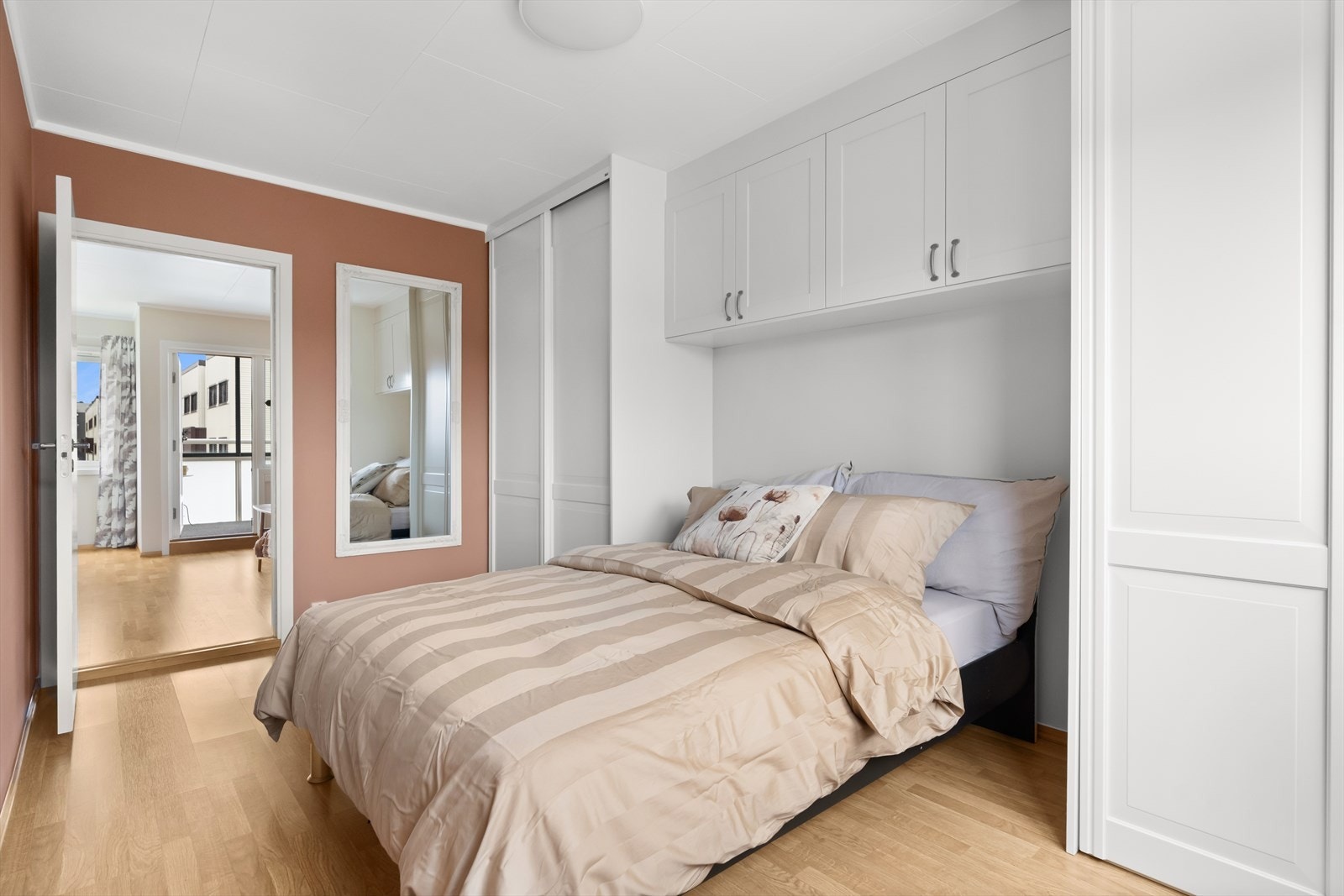 Smart garderobeløsning med nisje for dobbeltseng, skyvedørsgarderober på hver side og veggskap med profilerte fronter. Galleribilde