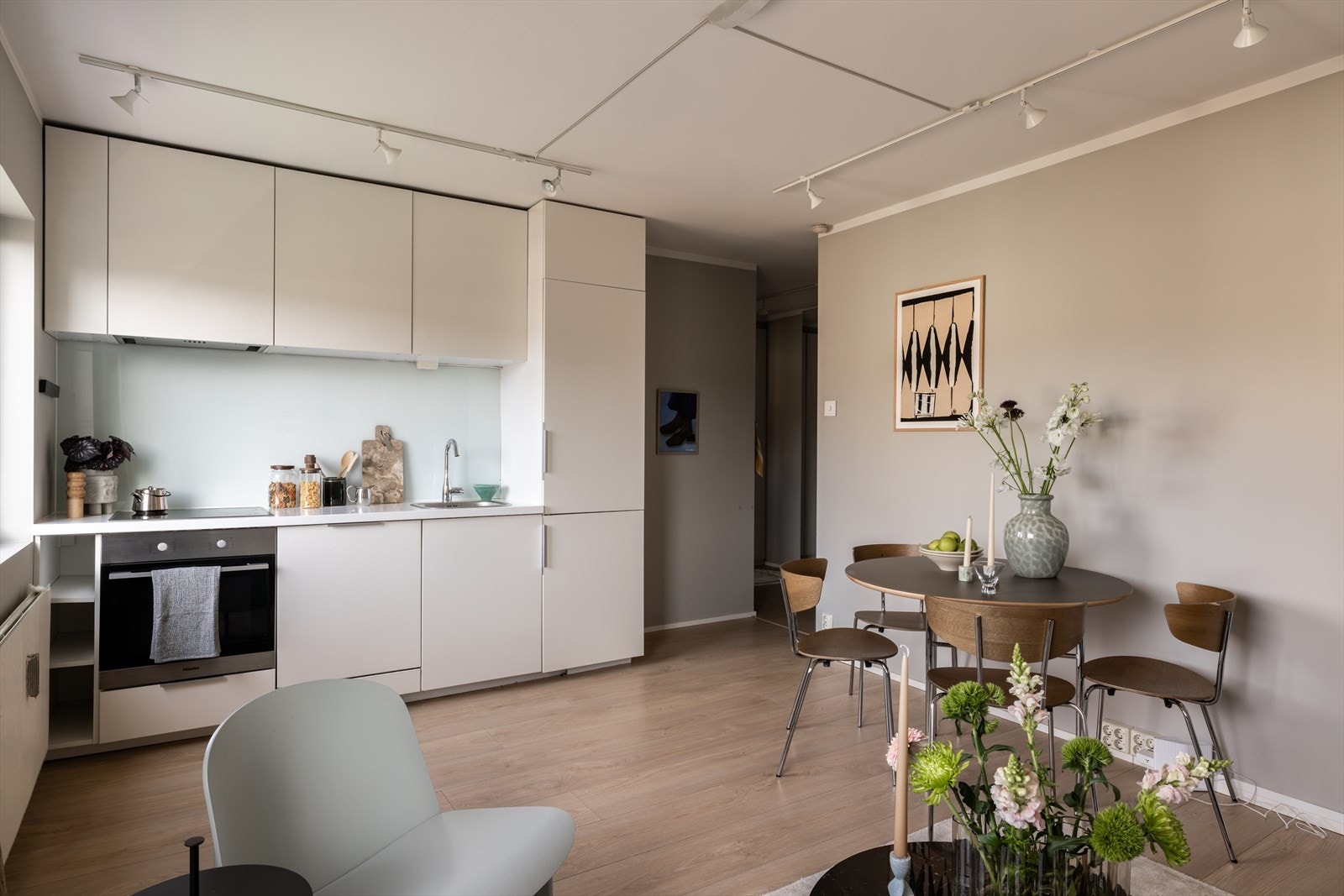 Pent kjøkken med lyse fronter, glassplate på vegg over benkeskap og laminat benkeplate. Galleribilde