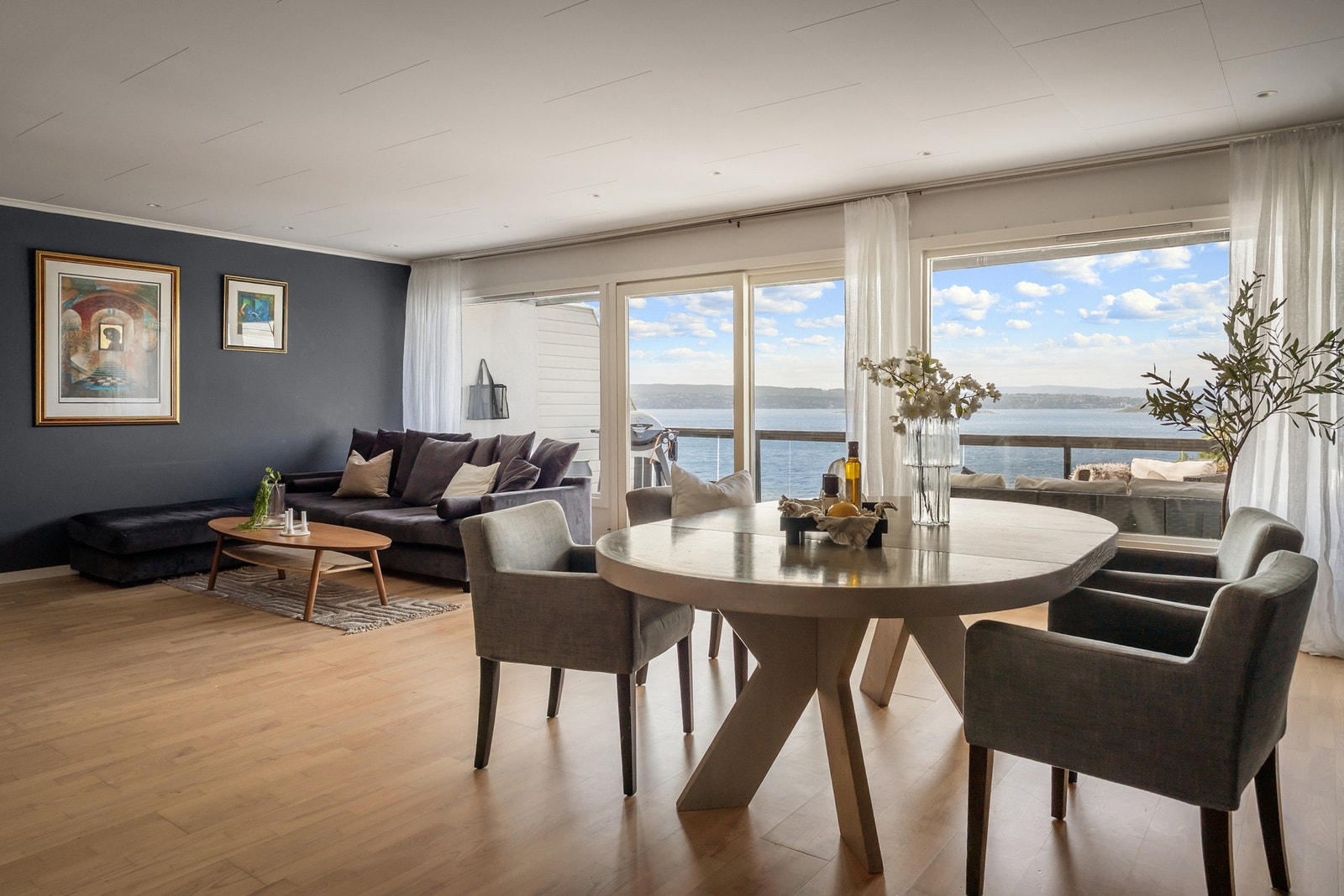 Luftig stue med panoramavinduer og skyvedør til veranda - fjordutsikten setter en unik stemning i rommet Galleribilde