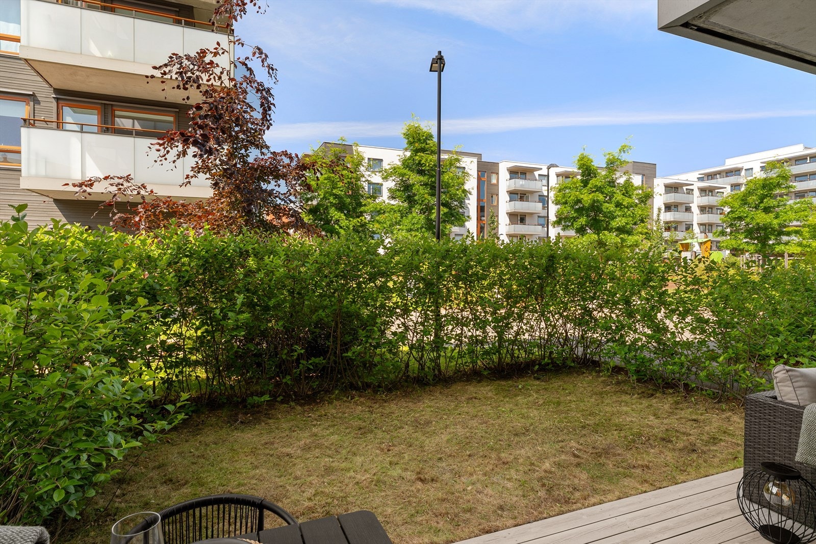 Terrassen ligger skjermet til med plen og hekk Galleribilde