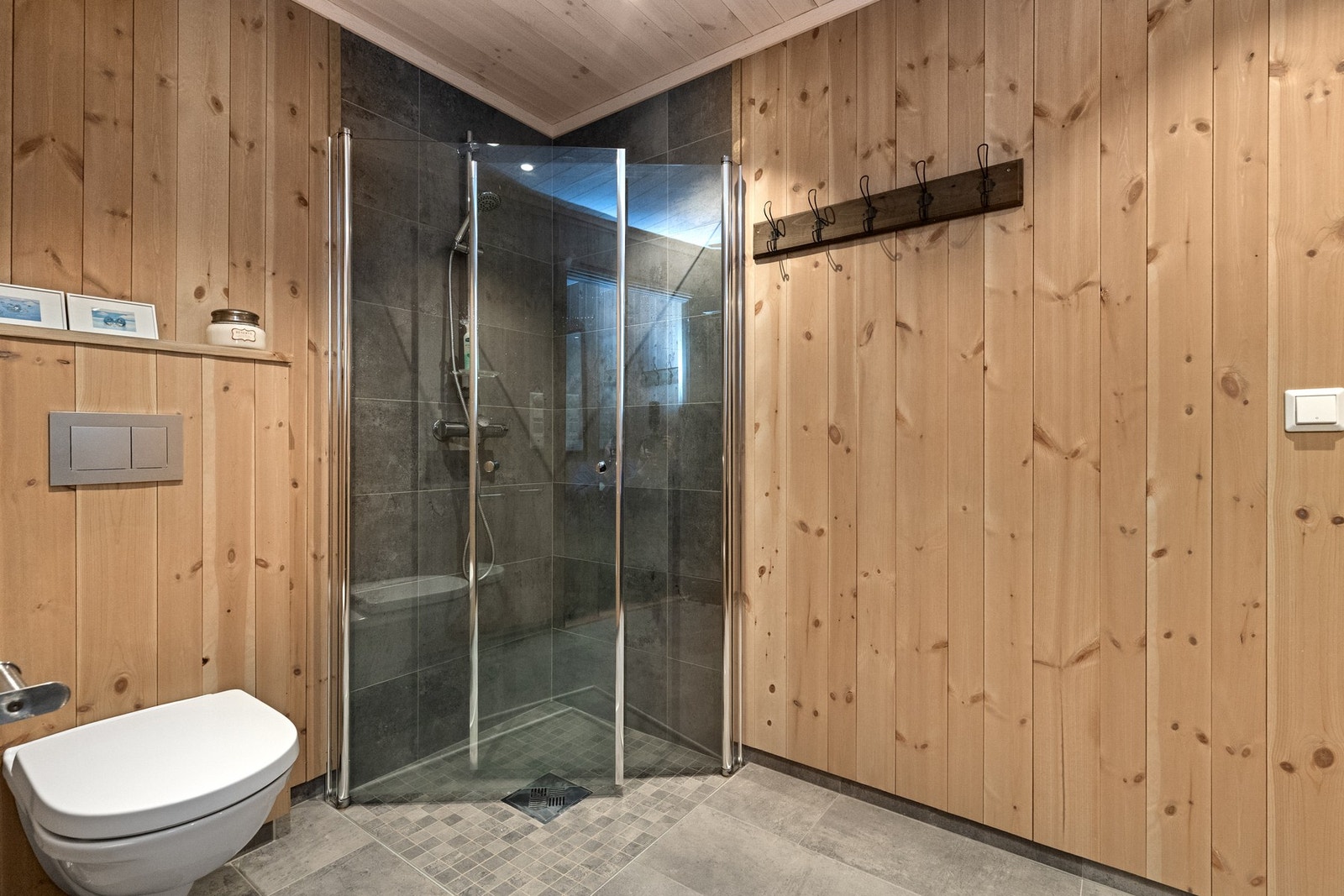 Badet har flislagt gulv og dusjnisje, panel på vegger Galleribilde