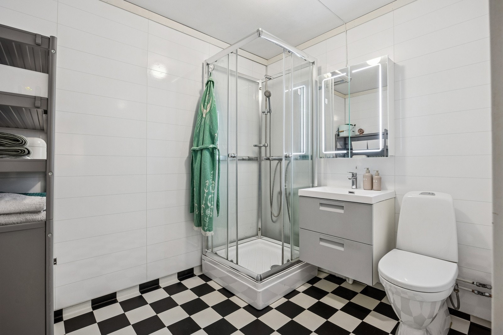 Badeom med dusjkabinett, plater på vegger og våtromsbelegg på gulv. Toalett. Galleribilde