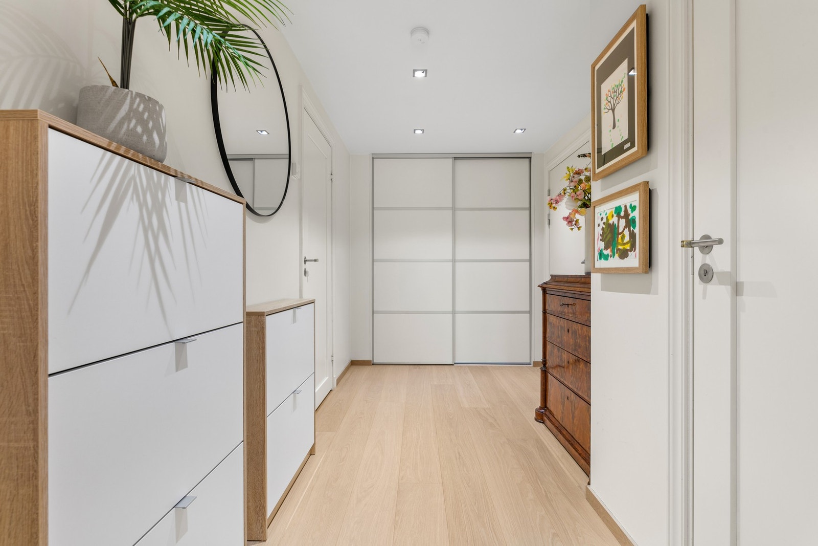 Den romslige entréen er utstyrt med en skyvedørsgarderobe med hvite fronter Galleribilde