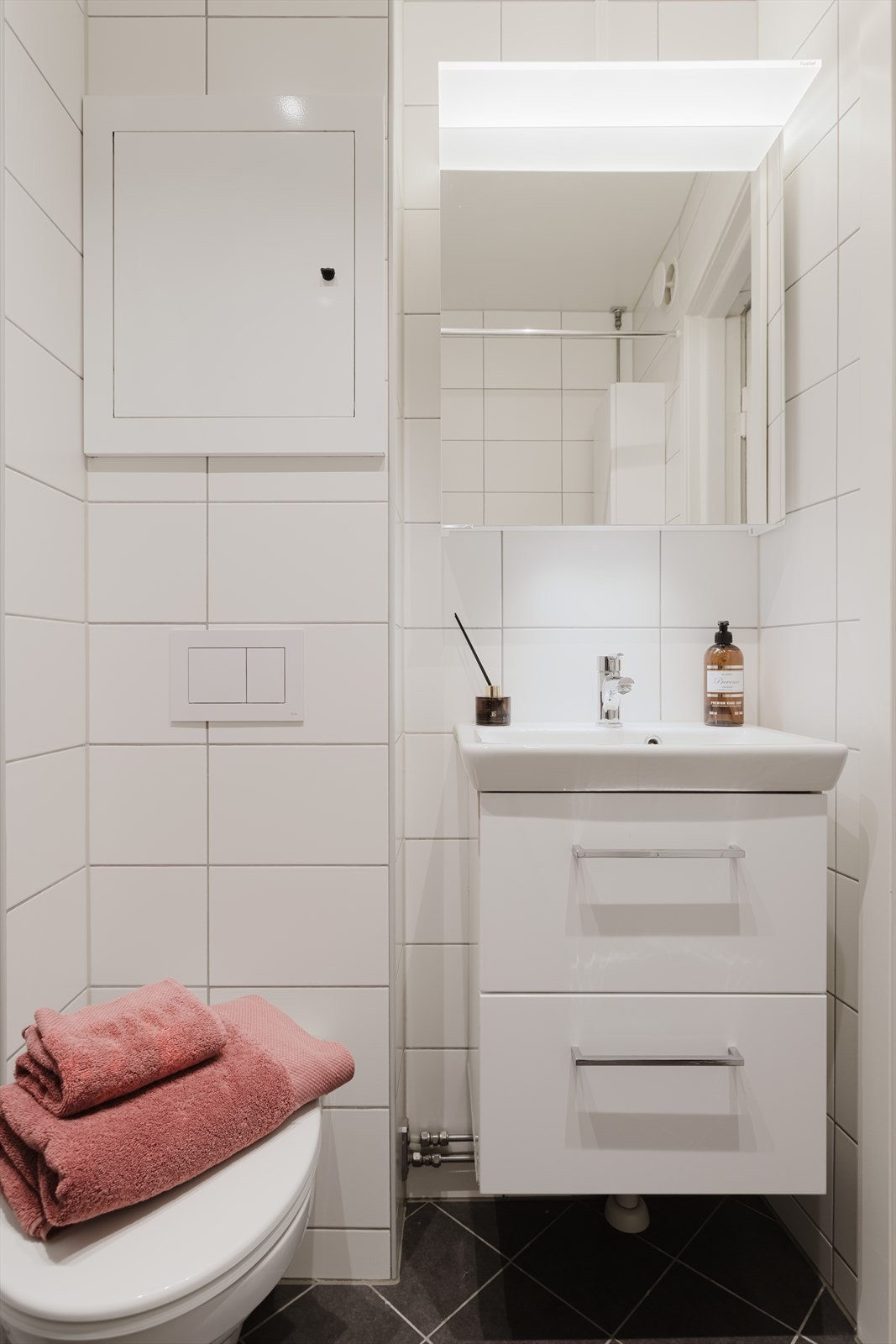 Badet har også servant på underskap med høyglansfolierte fronter, speilskap og veggmontert klosett Galleribilde