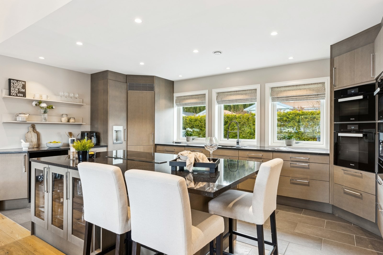 Dette er et kjøkken som oser kvalitet og tidløs eleganse. Med steinbenkeplate som både tåler hverdagen og imponerer gjestene, er dette et naturlig samlingspunkt i hjemmet. Galleribilde