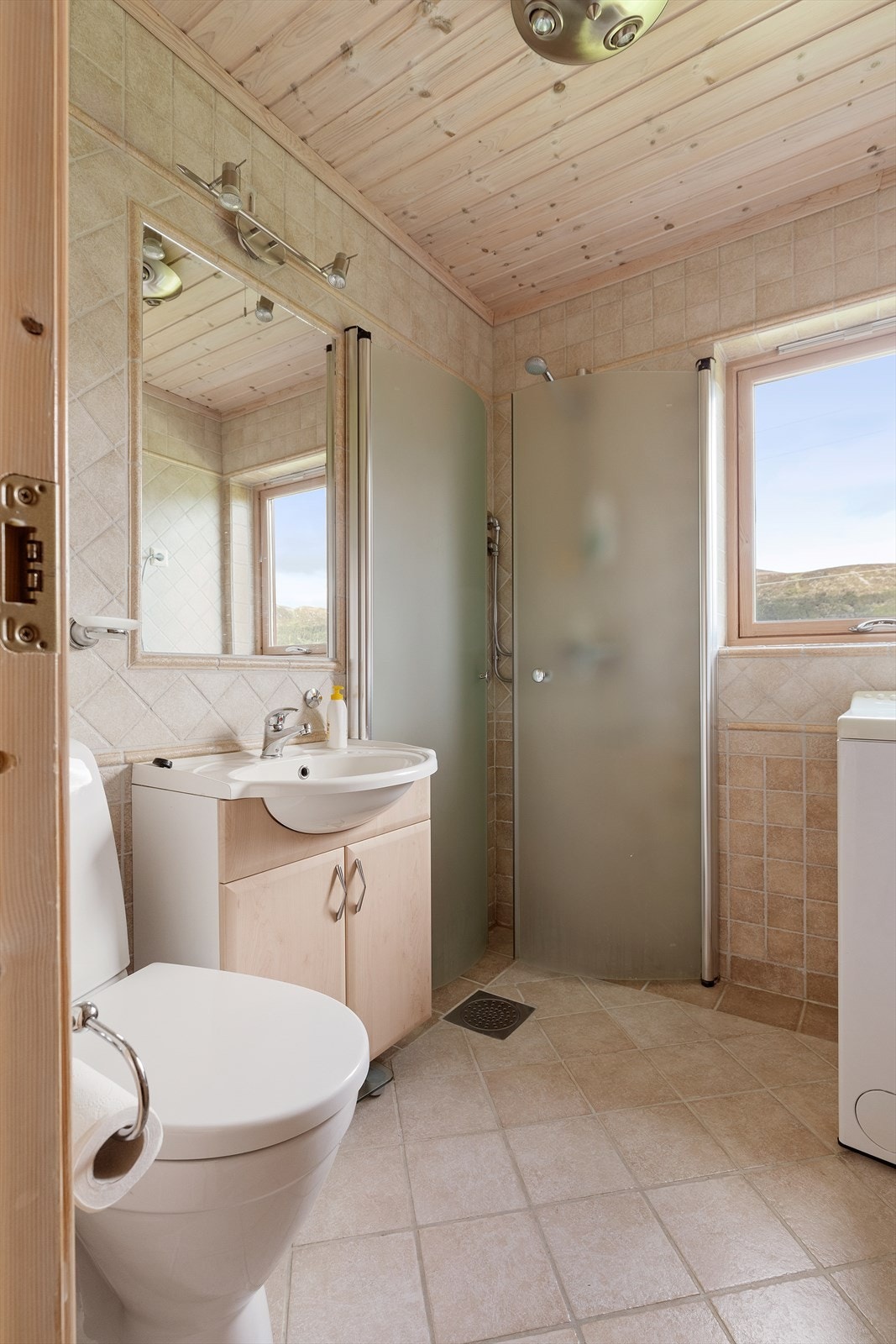 Flislagt bad med dusjhjørne og opplegg til vaskemaskin Galleribilde