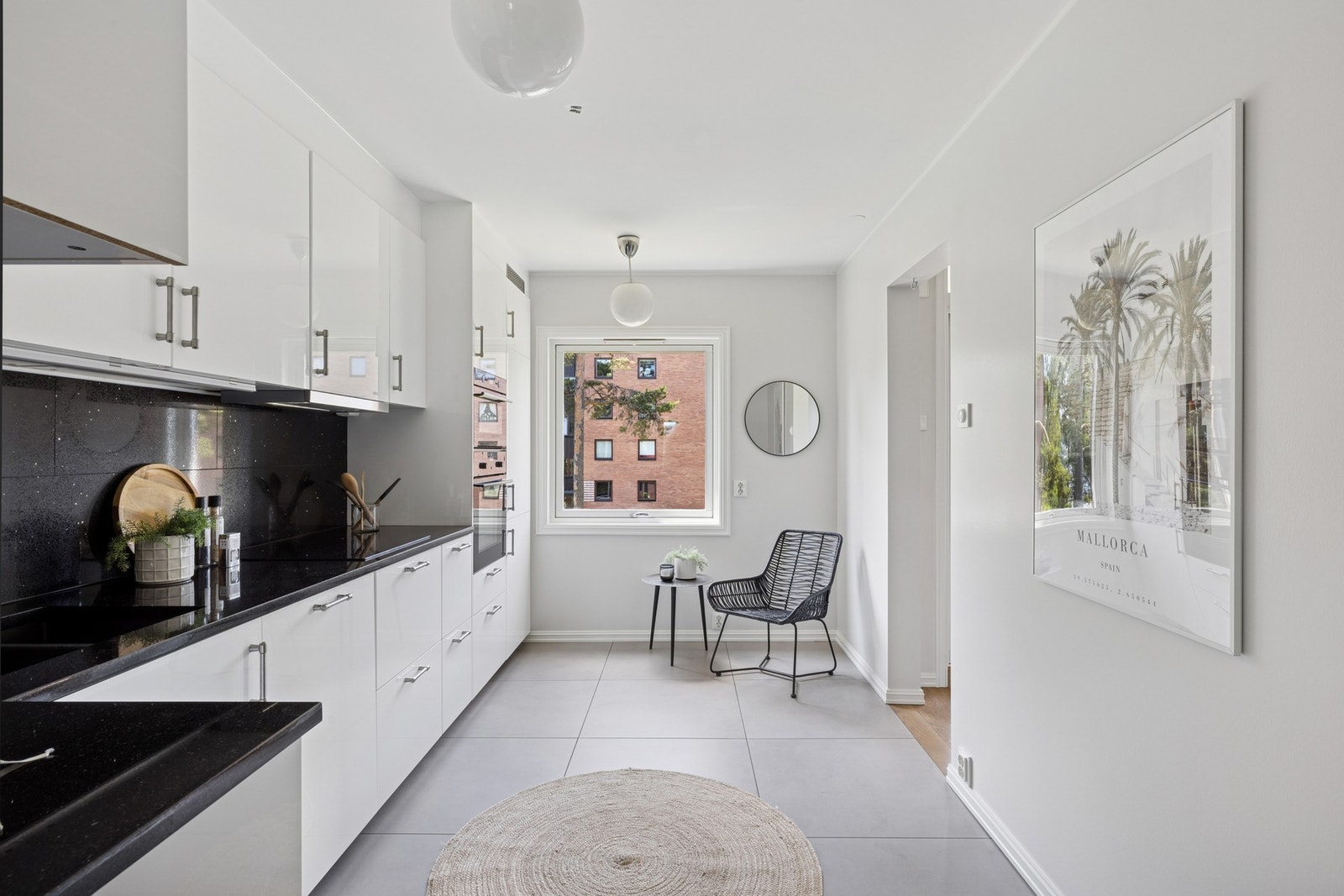 Lyst og moderne kjøkken med spiseplass ved vinduet og store fliser med gulvvarme for økt komfort. Galleribilde