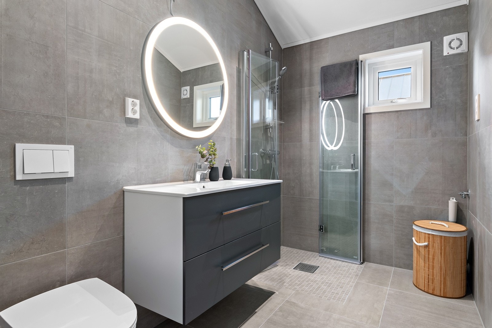 Badet er helfliset og har varmekabler i gulvet. Stilrene flisvalg, en fin servant med innredning og tilhørende sminkespeil, samt dusj med innfellbare vegger. Galleribilde