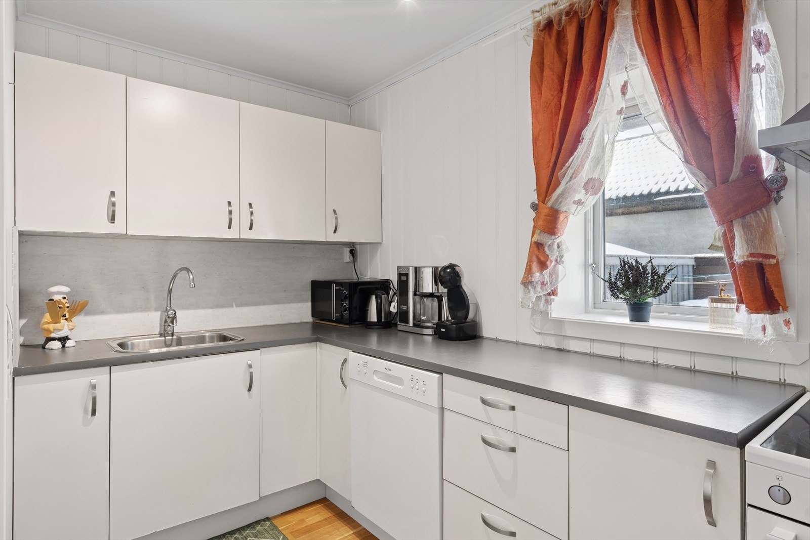 Kjøkkeninnredningen har glatte, hvite fronter og tilstrekkelig med plass for oppbevaring. Galleribilde