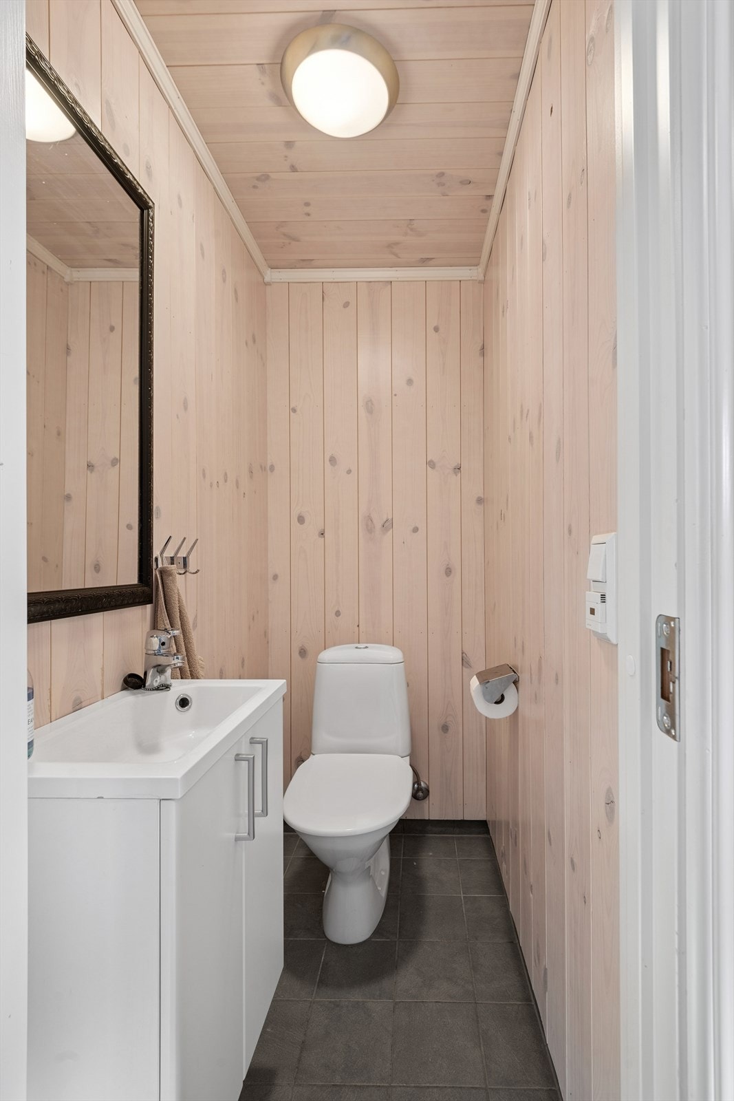 Toalettrom innredet med servant med underskap, speil og gulvmontert toalett. Galleribilde