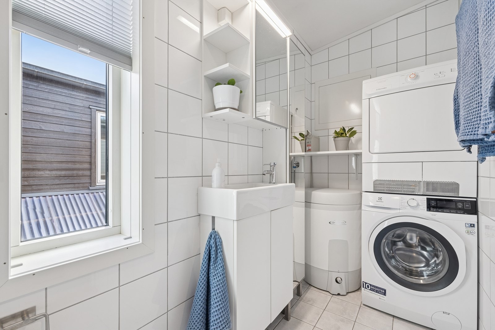 Opplegg for både vaskemaskin og tørketrommel, samt lys og moderne baderomsinnredning. Galleribilde