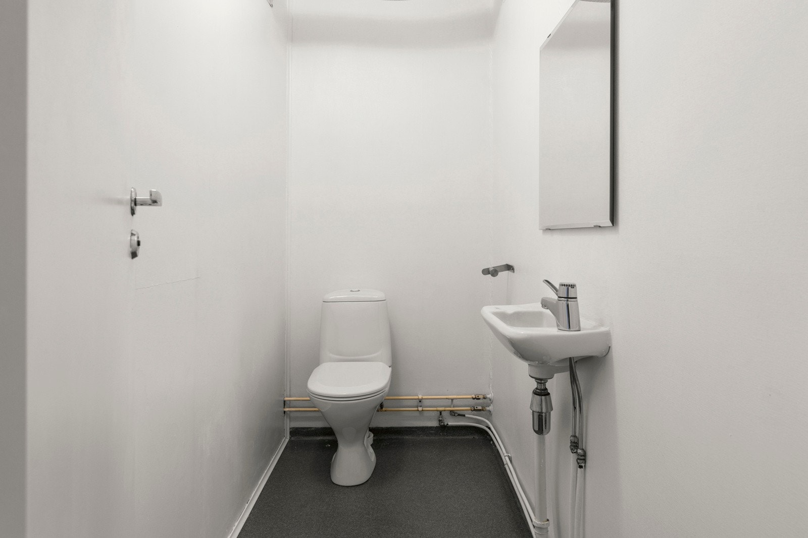 Det separate toalettrommet er innredet med toalett og veggmontert servant med speil overover Galleribilde