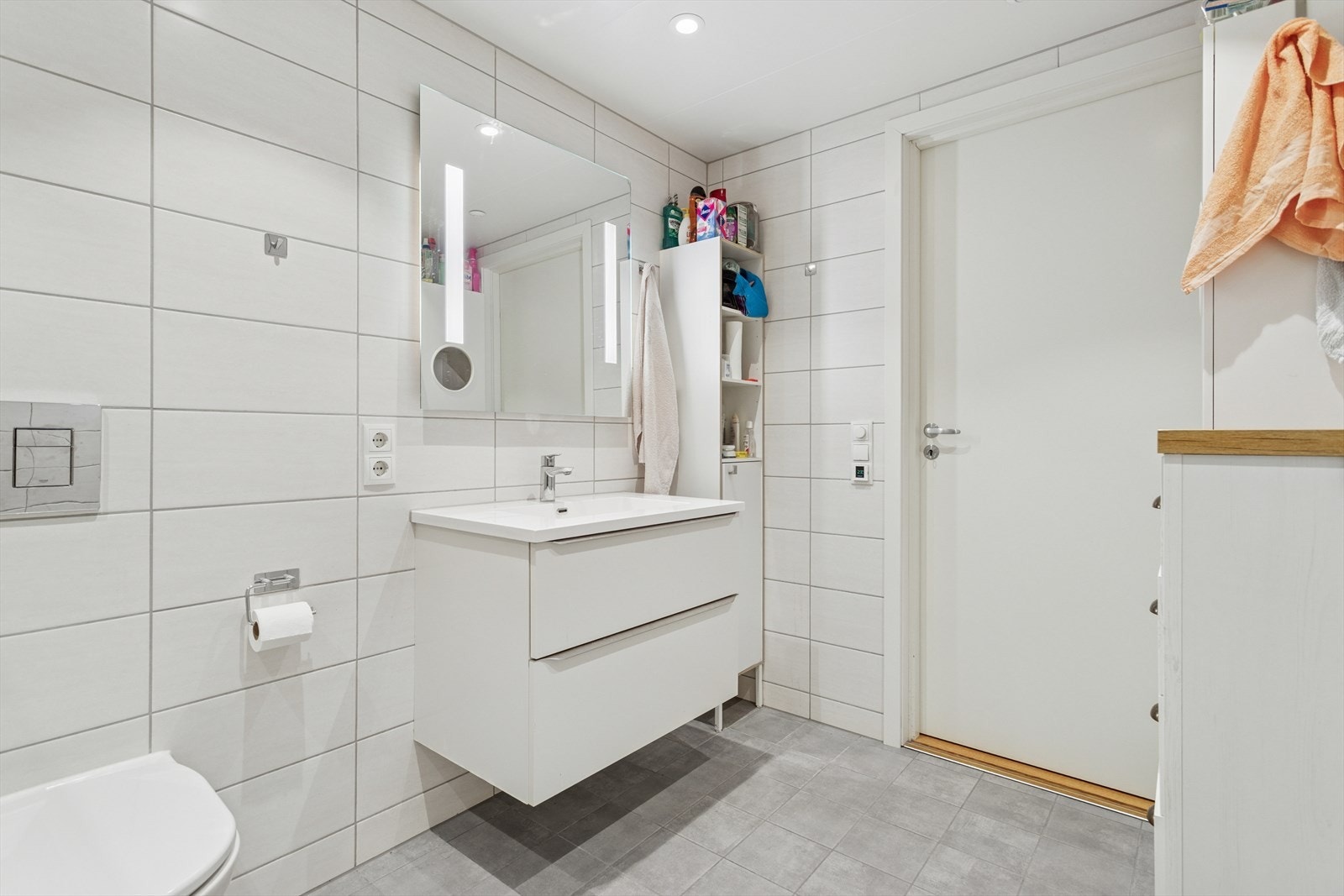 Badet har dusjvegger av glass, vegghengt toalett, innredning med servant samt opplegg for vaskemaskin. Galleribilde