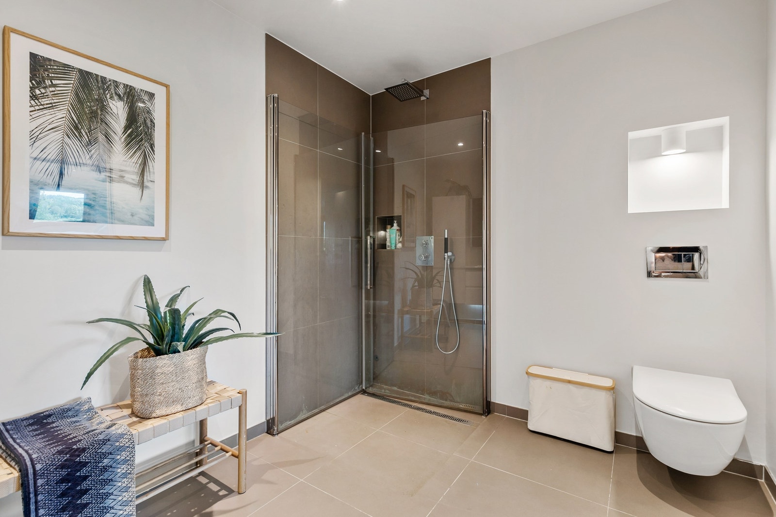 Vegghengt toalett. Dusj i hjørne. Innebygget dusjbatteri tilkoblet veggmontert hånddusj og regnfallsfunksjon. Mekanisk avtrekksventilasjon med fraluftsventil plassert i himling. Galleribilde