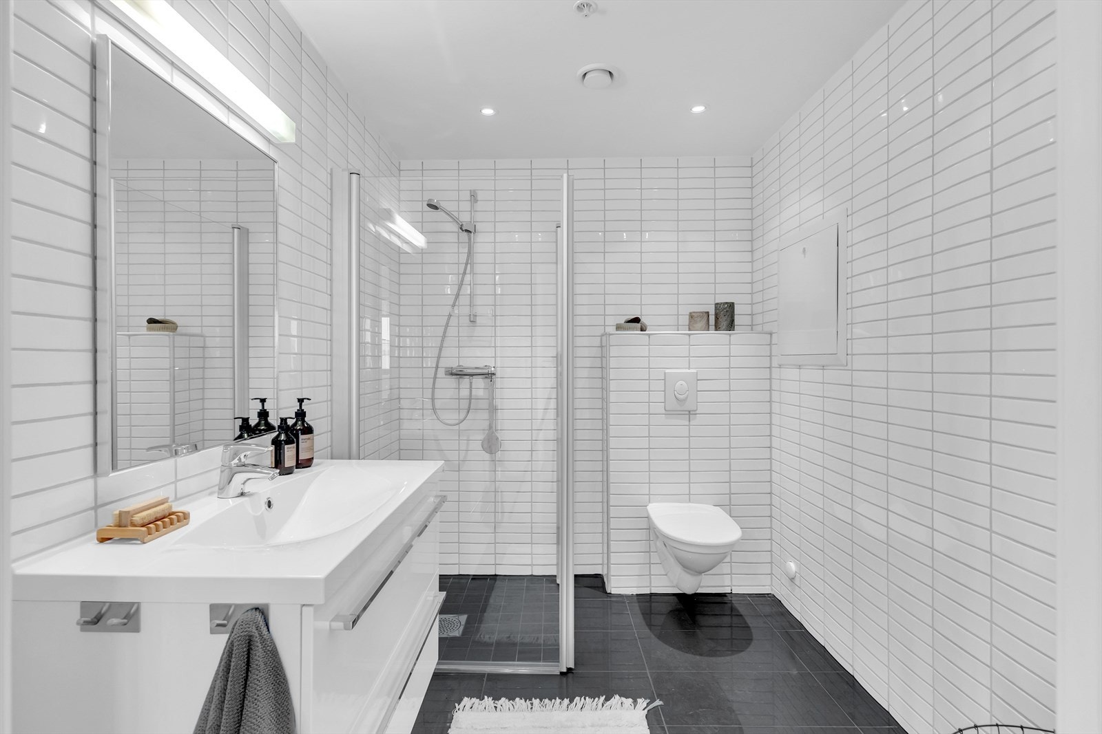 I tilknytning til soverommene i 1. etasje finner man et pent innredet bad. Badet er utstyrt med varmekabler u gulv, dusj m/innfellbare glassdører, heldekkende servant, speil og vegghengt toalett og downlightsbelysning. Galleribilde