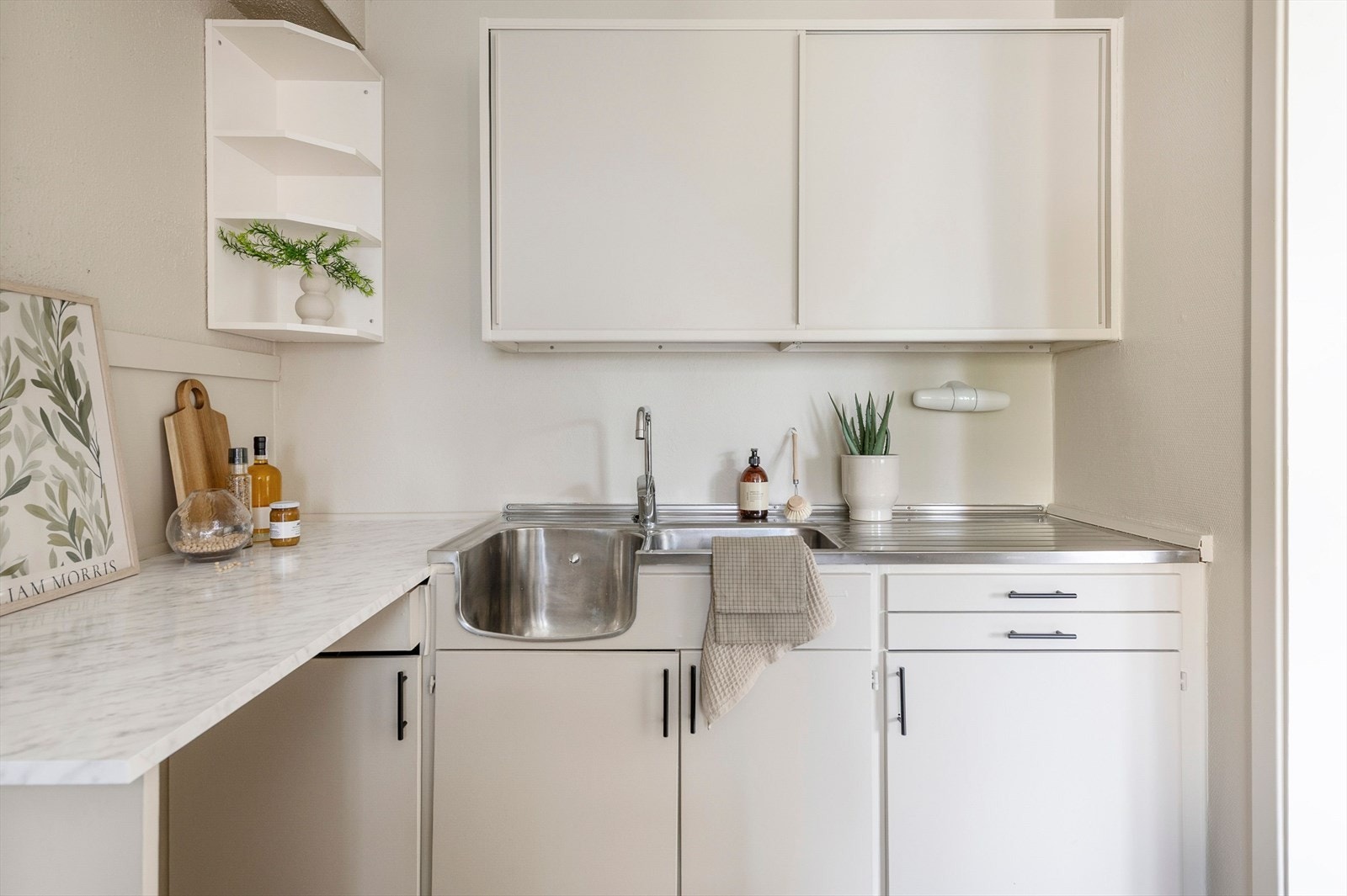 Eldre kjøkken som er overflatefornyet med maling og nye håndtak. Galleribilde