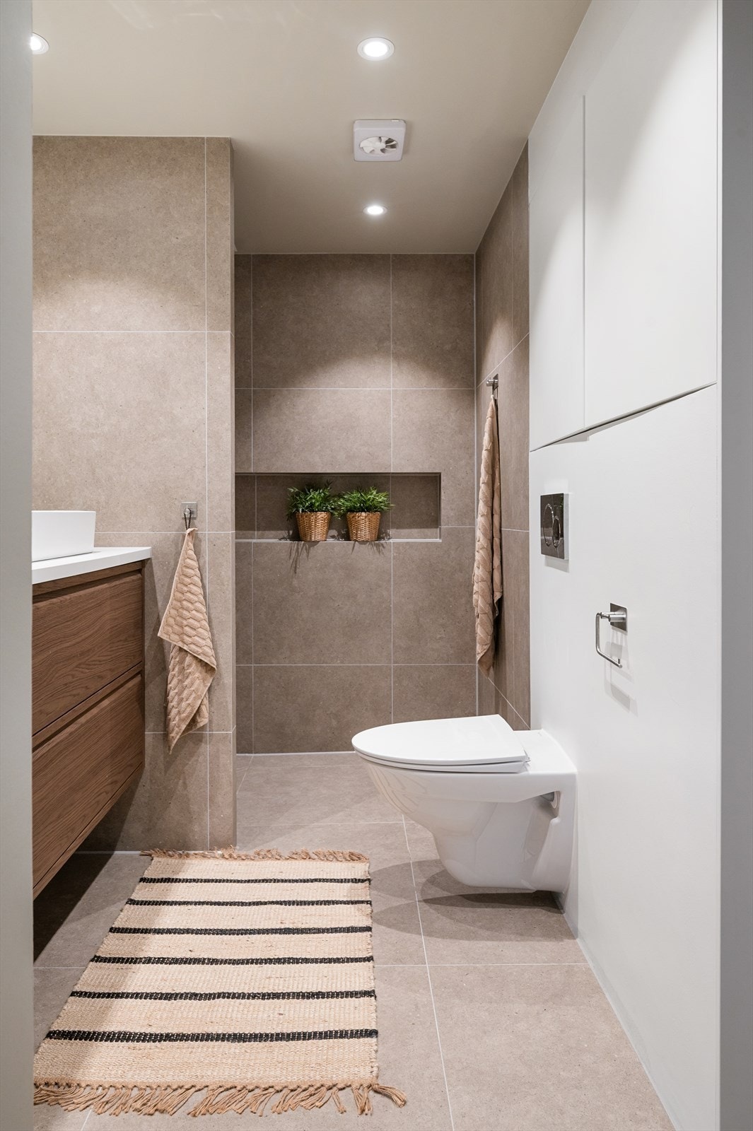 Badet er utstyrt med vegghengt klosett, servant på laminat benkeplate og dusjnisje med glassdør. Galleribilde