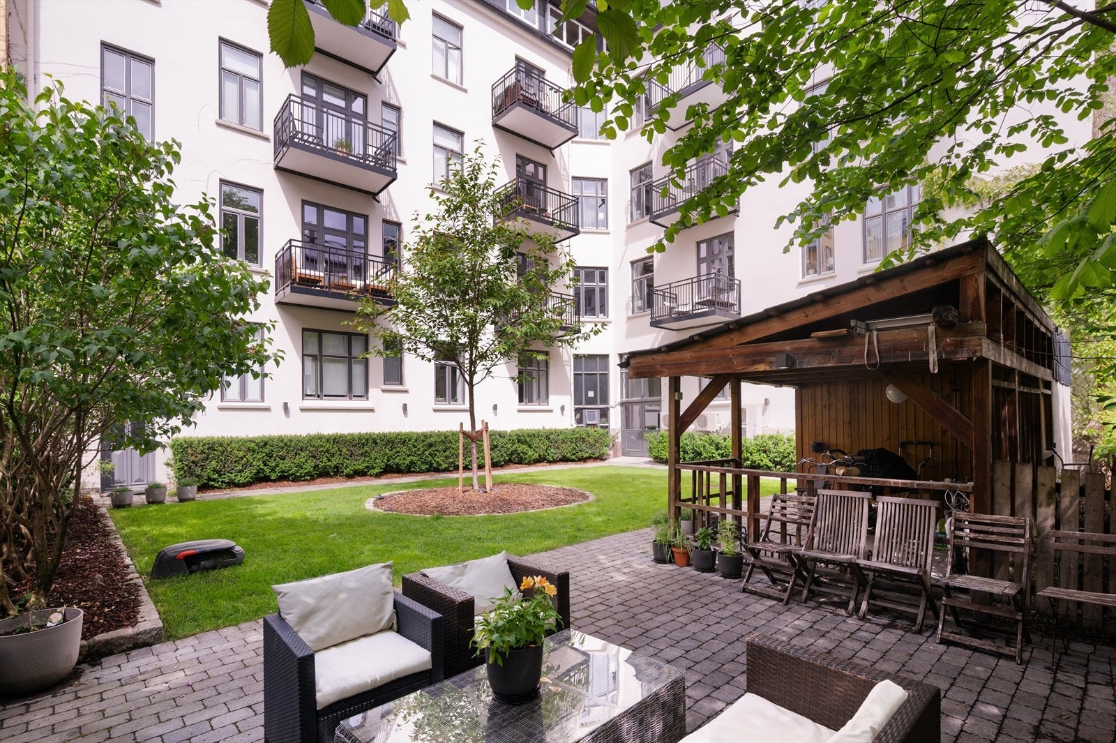 Pent opparbeidet indre gård med grønn beplanting, sittegrupper og sykkelparkering. Galleribilde