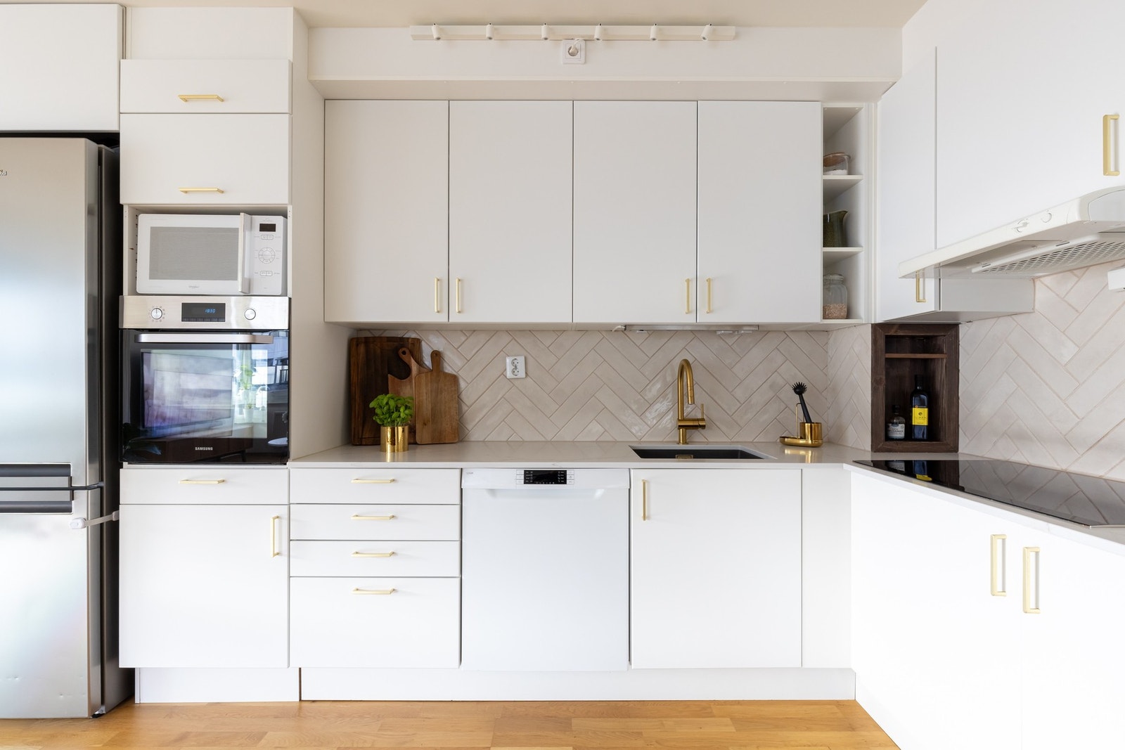 Lekkert og stilrent Aubo-kjøkken med hvit, glatt innredning og moderne fliser mellom benkeplate og overskap. Integrerte hvitevarer som stekeovn, platetopp, oppvaskmaskin og vinkjøler medfølger salget. Galleribilde