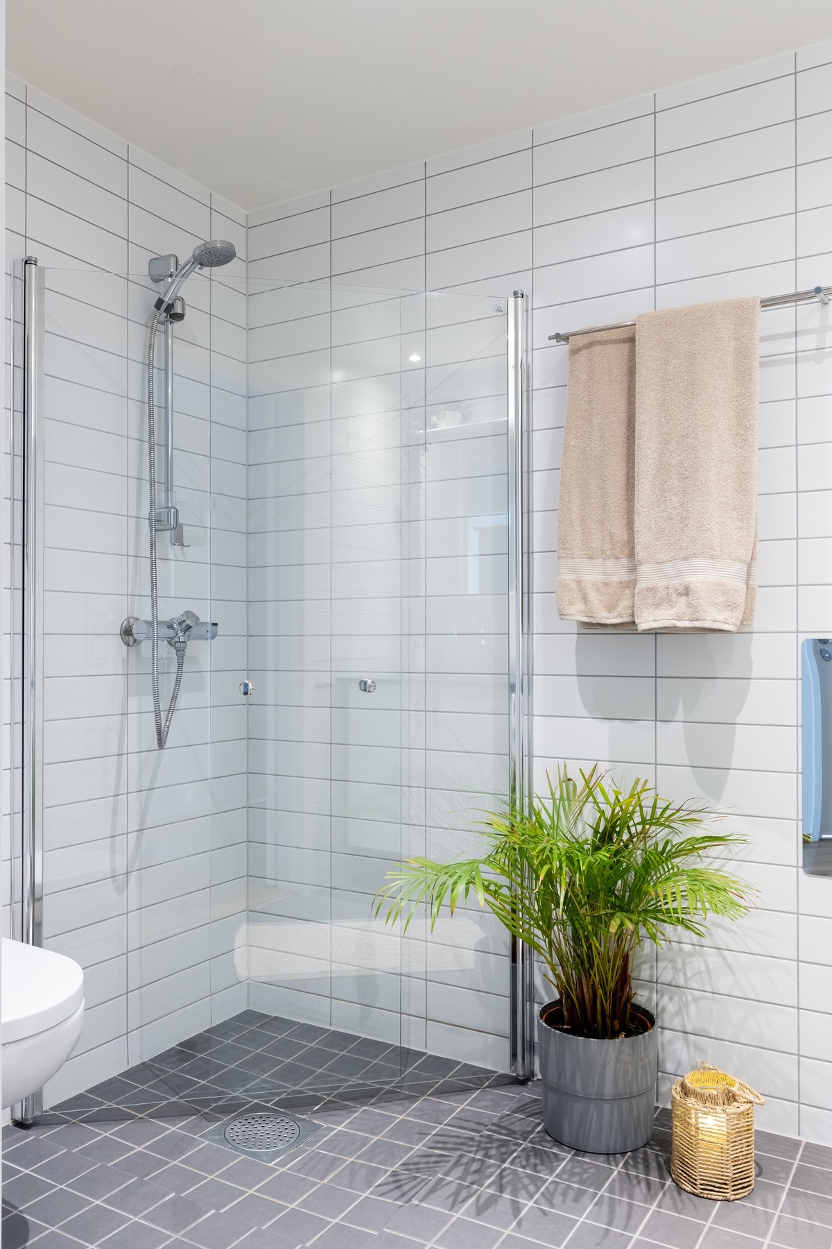 Videre er det vegghengt toalett og nedsenket dusjhjørne med hånddusj og innfellbare glassdører som frigjør plass på gulvet. Galleribilde