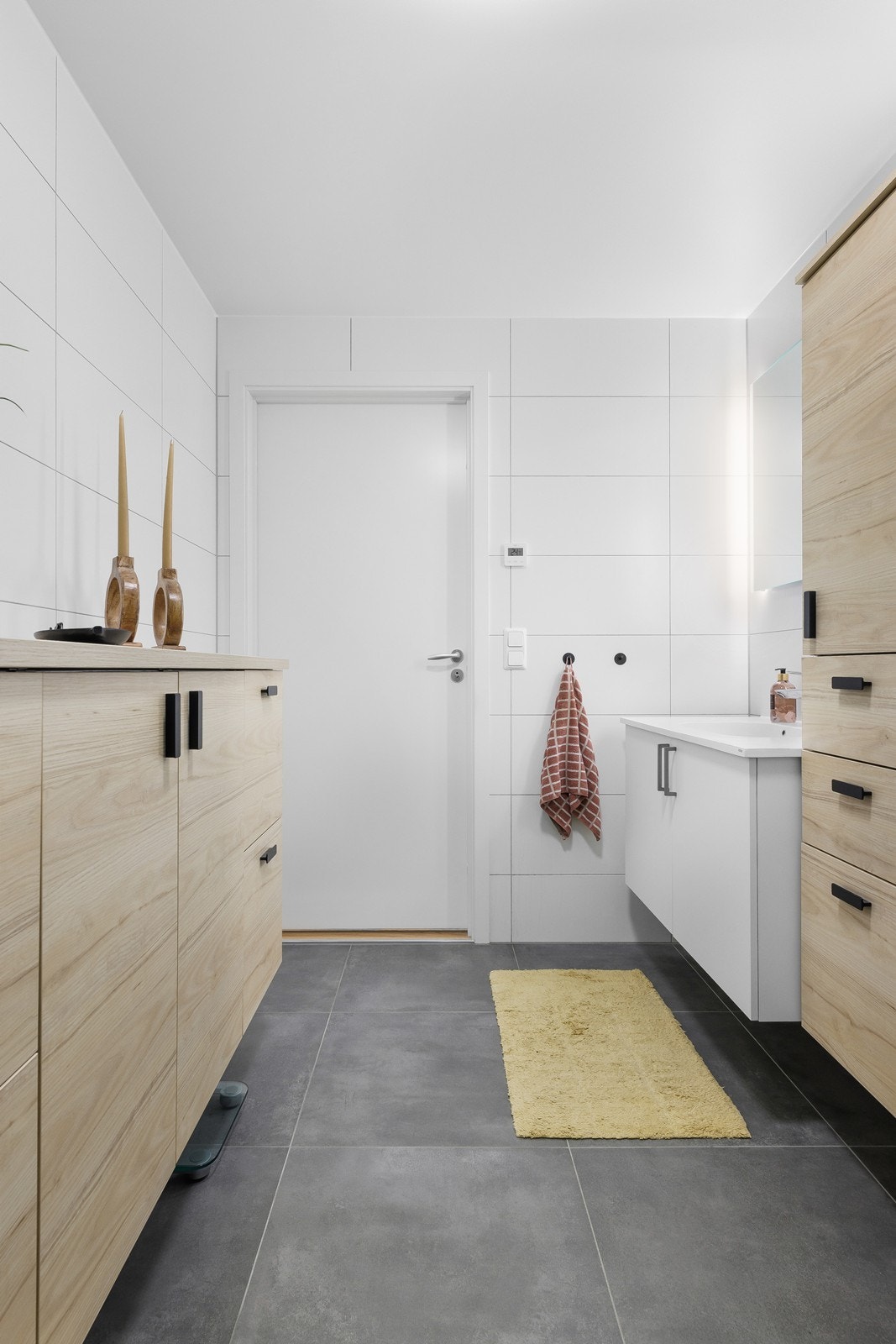 Grå 60x60 fliser på gulv og lyse fliser på vegg - badet inneholder dusj, toalett, servant, speil og rikelig med oppbevaringsplass i skaper og skuffer. Galleribilde