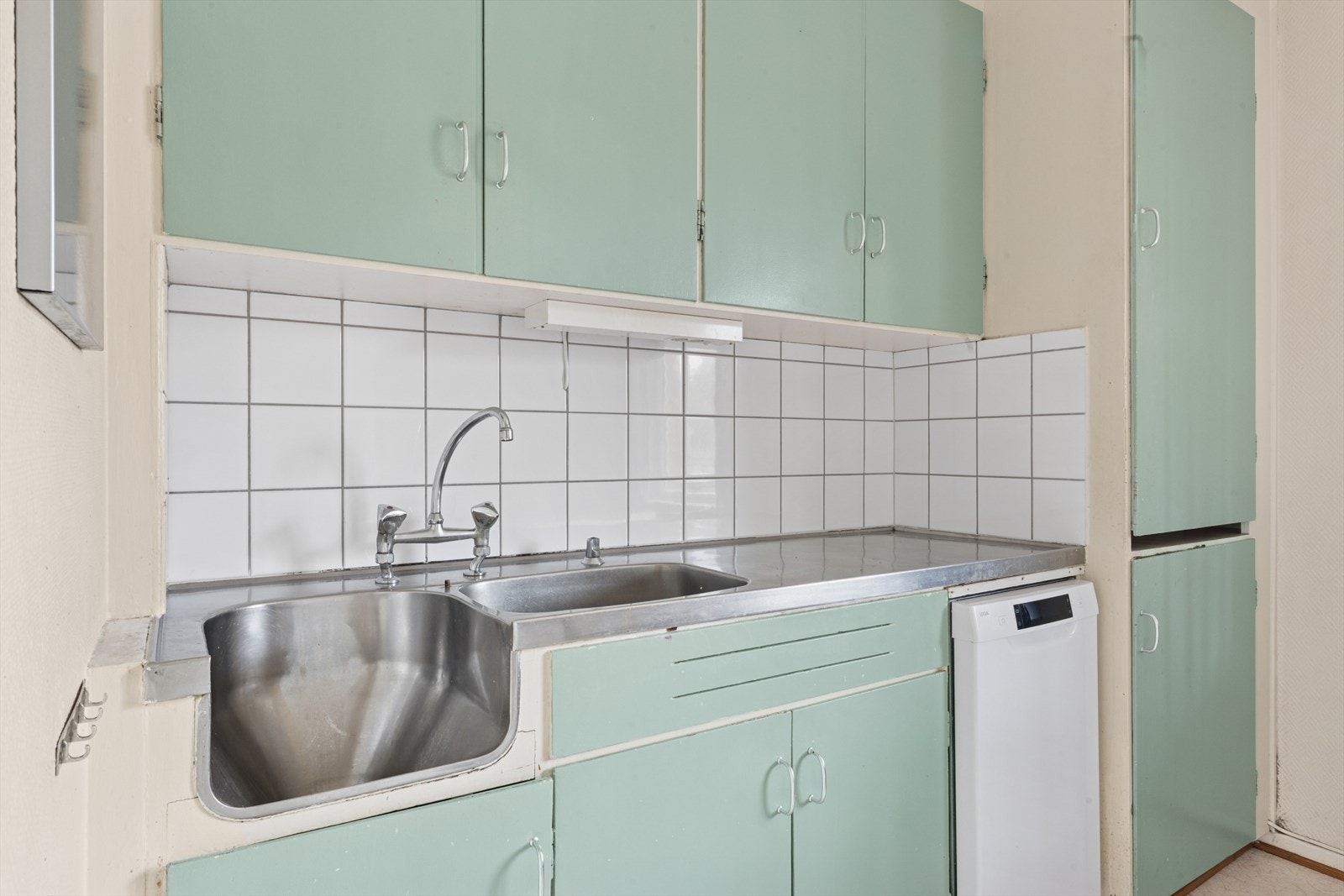 Kjøkkenet har en innredning av plassbygde skrog med malte slette fronter, laminert benkeplate med nedfelt oppvaskkum i stål med to-greps blandebatteri og belysning under overskap. Galleribilde