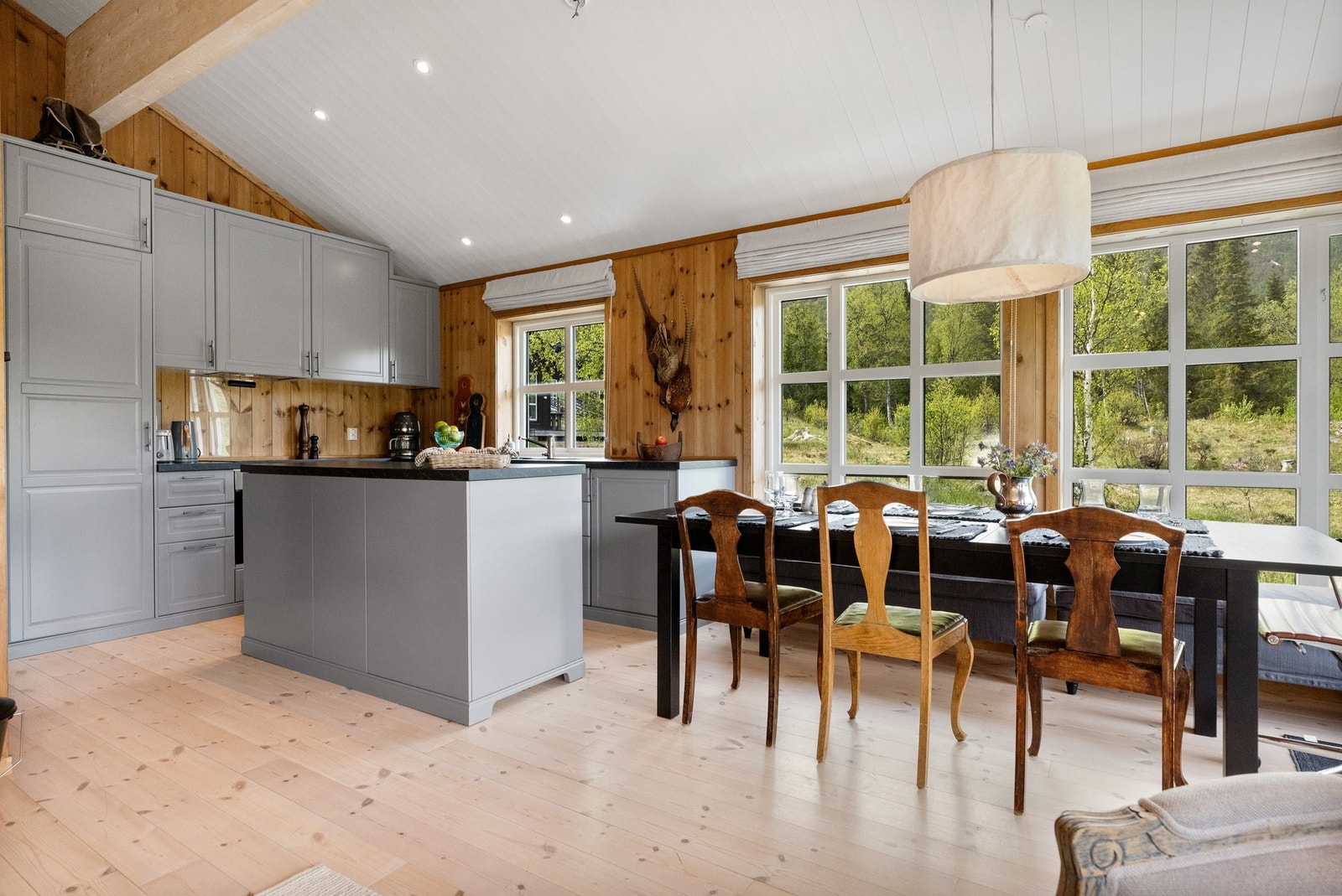 Den åpne løsningen gir mulighet for sosialt samvær med gjestene ved matlaging, det er plass til mange rundt bordet.
Kjøkkeninnredningen er gråmalt med håndtak som er i samme fargeutførelse som benkeplaten Galleribilde