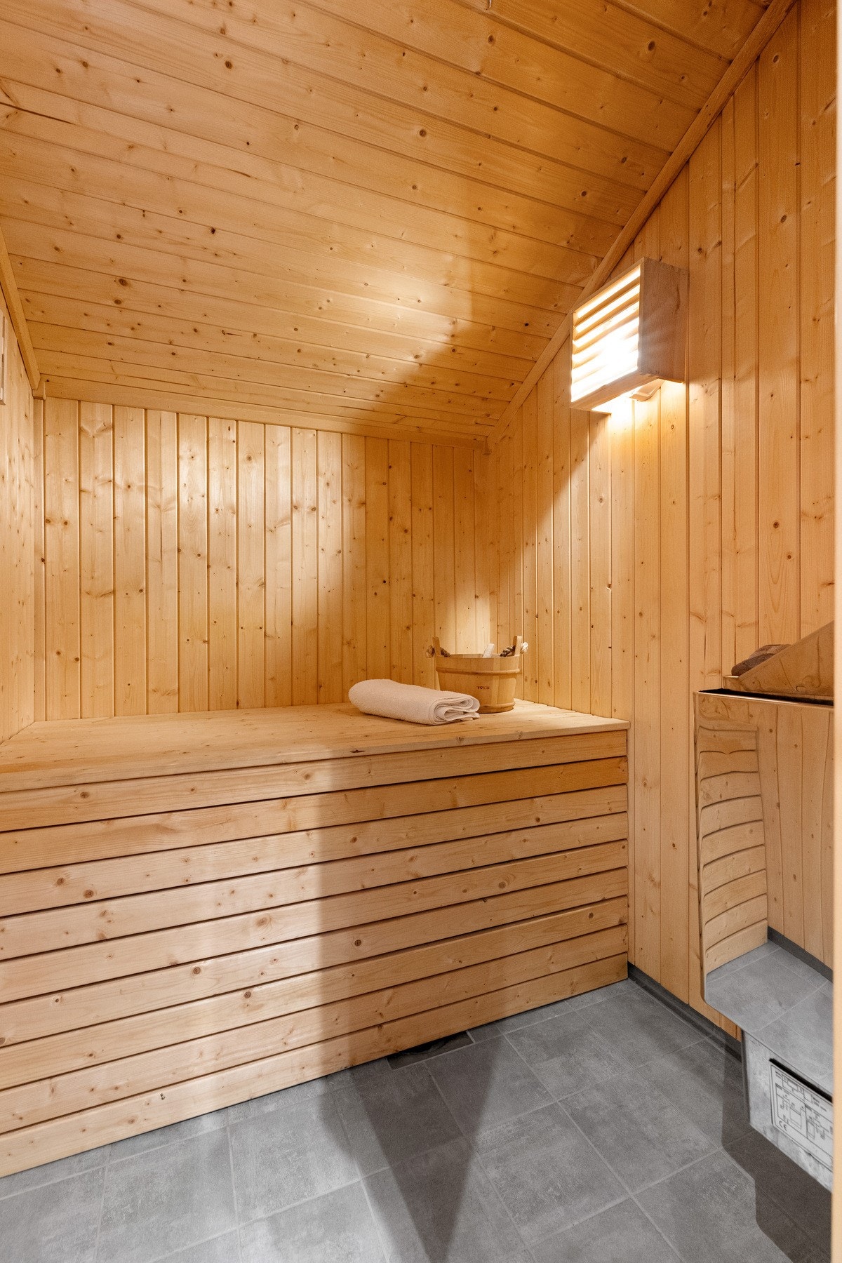 Badstue med fliser og varmekabler på gulv. Bred sittebenk, varmtvannsbereder på ca. 200l er plassert inni. Galleribilde