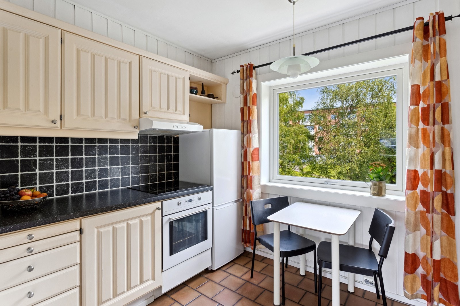 Kjøkken med lys kjøkkeninnredning med malte fronter, laminat bekeplate og fliser over vegg. Opplegg for oppvaskmaskin. Galleribilde