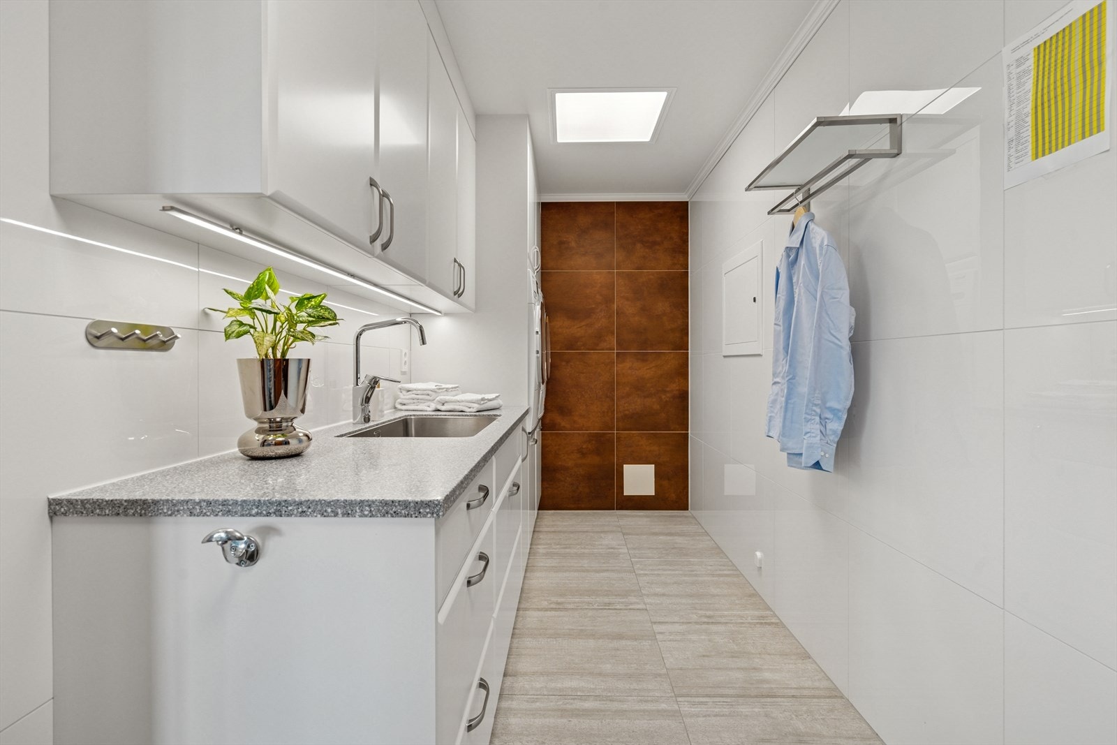 Det er flislagte overflater og en funksjonell innredning fra 2021 levert av Nygård - Innredningen har mye oppbevaringsplass, benkeplate med nedfelt utslagsvask og egnet plass iståhøyde for vaskemaskin/tørketrommel Galleribilde