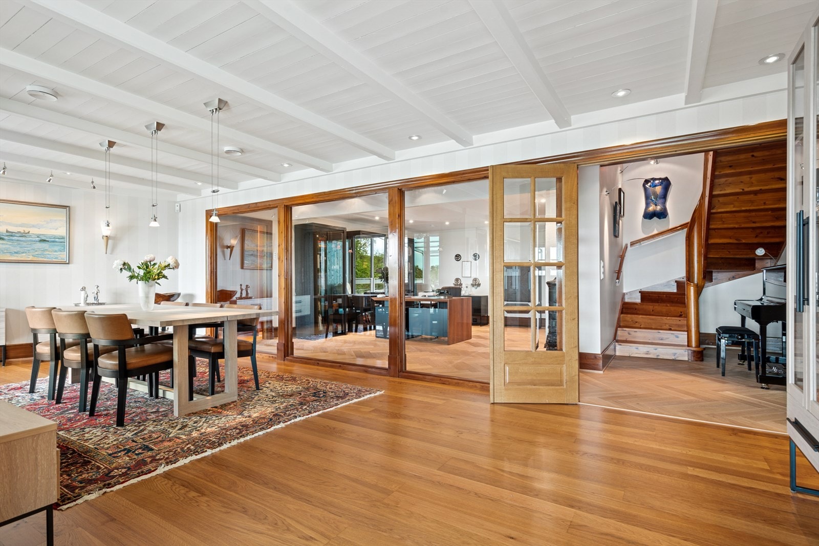 Glassveggen mellom spisestuen og biblioteket deler av rommene, samtidig som en beholder følelsen av rom og lys Galleribilde