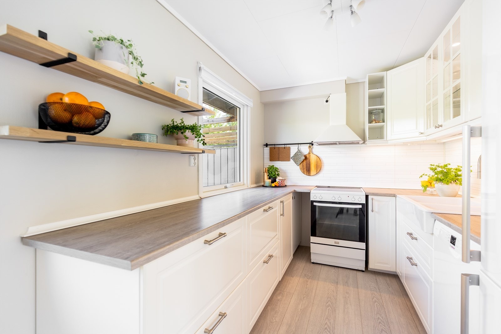 Kjøkkenet er lyst og pent med profilerte fronter, laminerte benkeplater og fuktbestandige plater mellom over- og underskap. Galleribilde