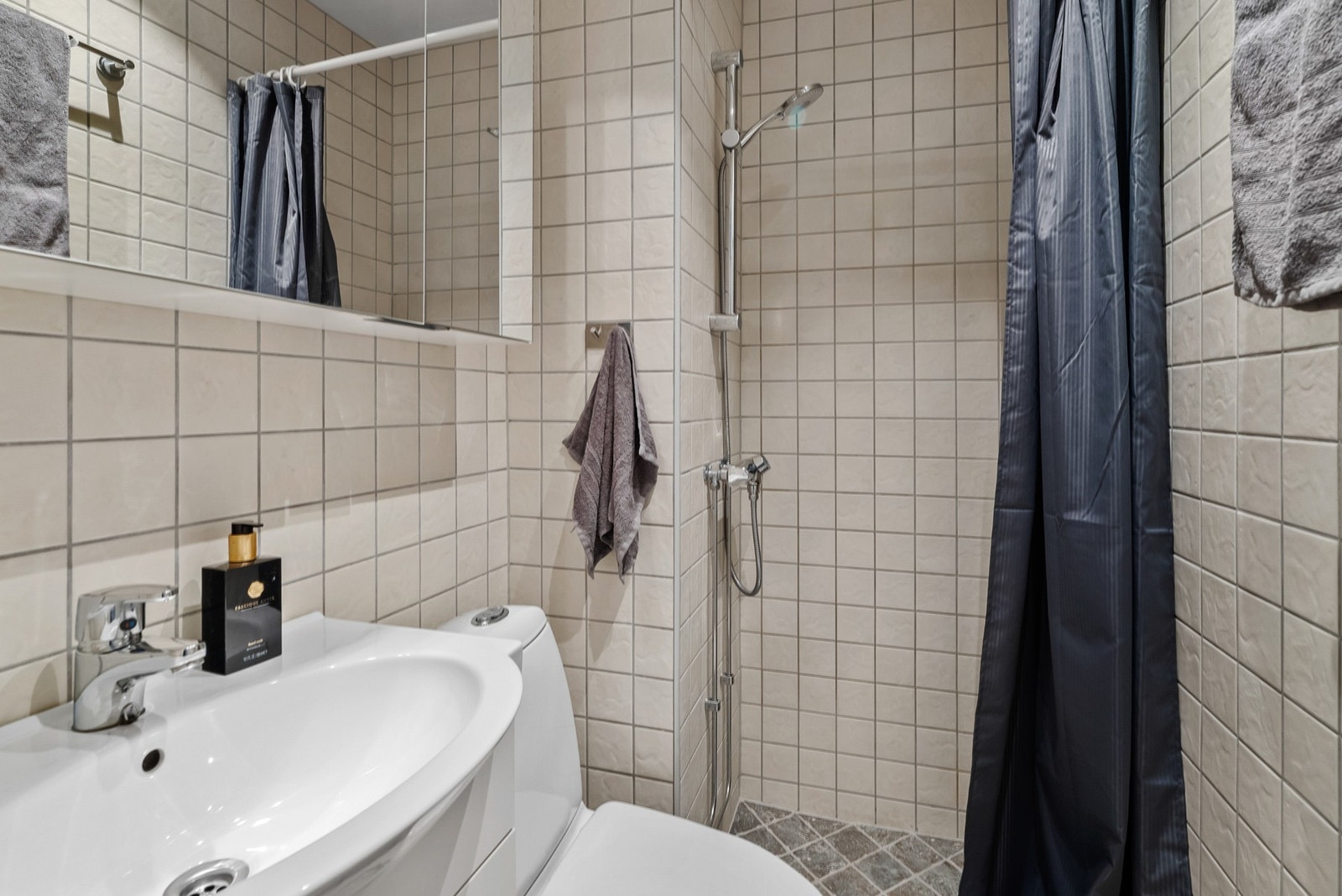 Flislagt bad med gulvvarme. Badet er innredet med servant, speilskap, toalett og dusjhjørne. Galleribilde