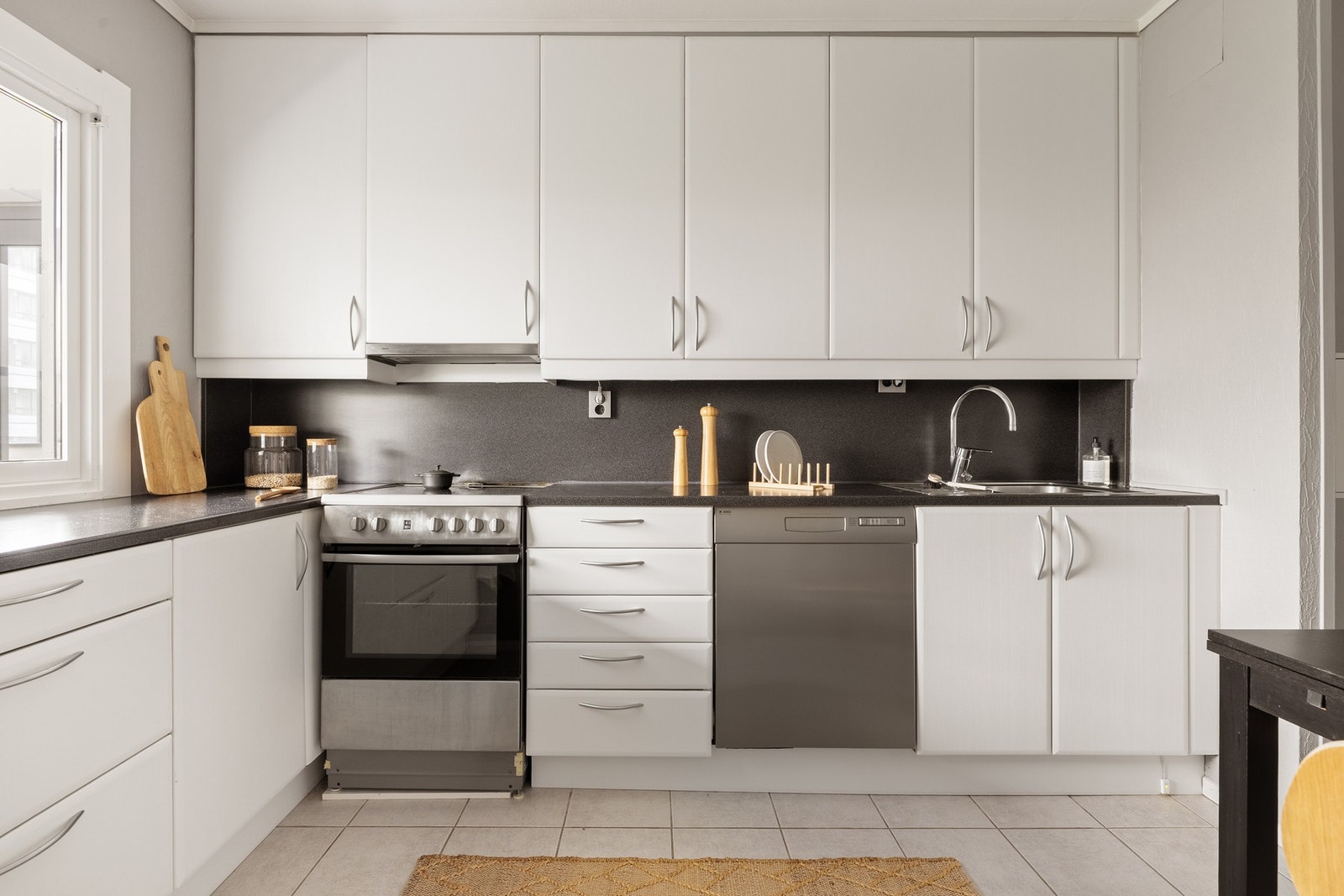 Kjøkkeninnredningen består av slette hvite fronter og laminat benkeplate med nedfelt vask av stål Galleribilde