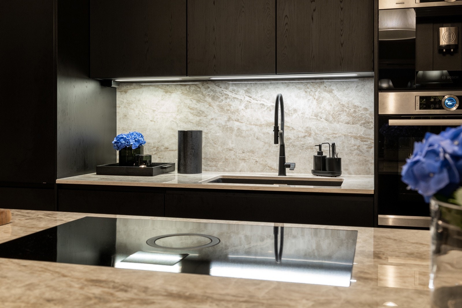 Moderne kjøkken med integrerte hvitevarer, mørke skapfronter og lys benkeplate. Galleribilde