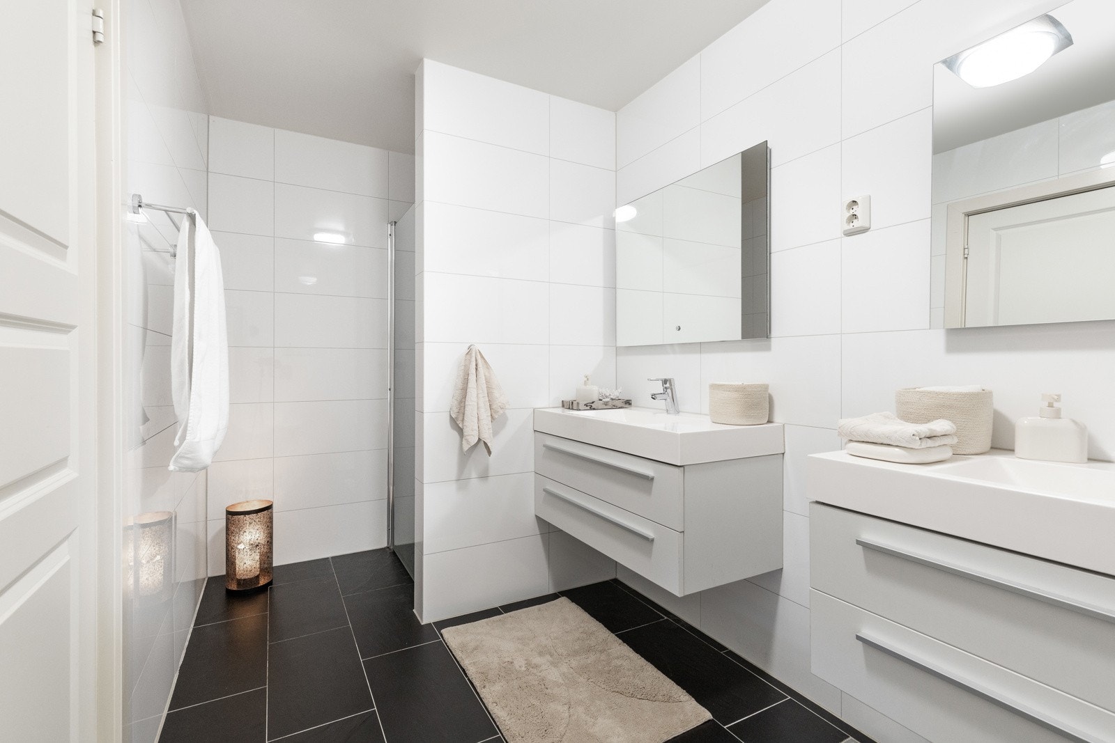 Lyst og moderne bad med flislagte vegger og gulv, samt to servantløsninger. Galleribilde