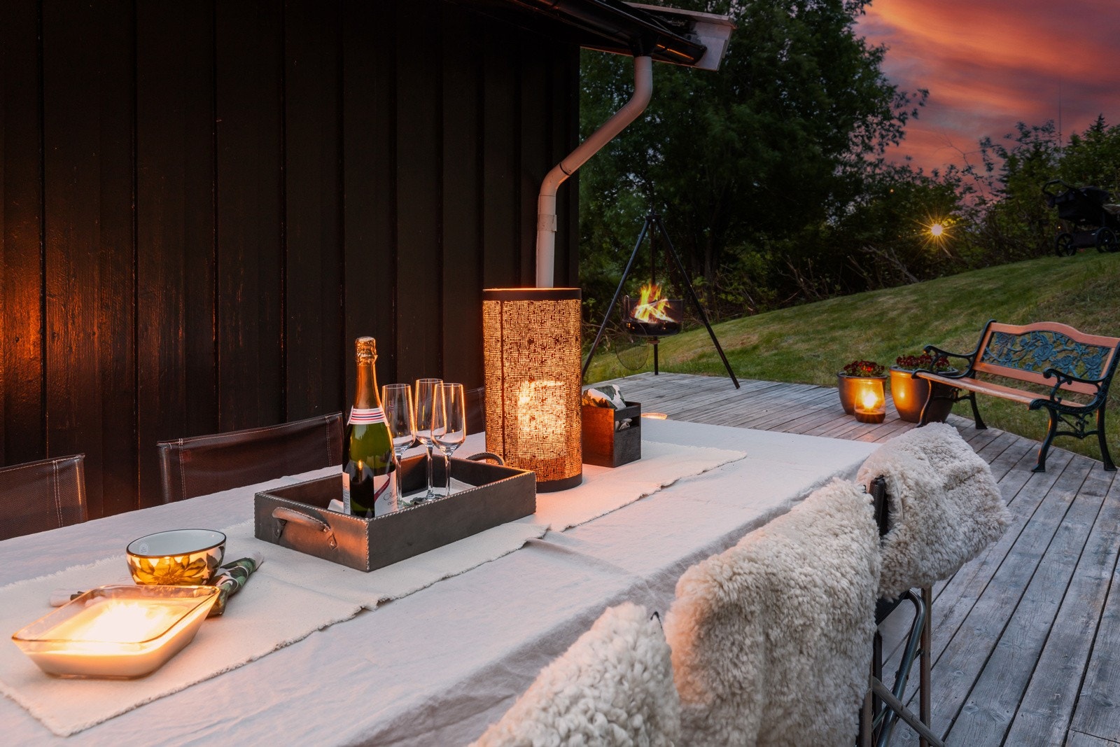 Koselig uteplass med terrassebor, omgitt av grøntareal og stemningsfull belysning. Galleribilde
