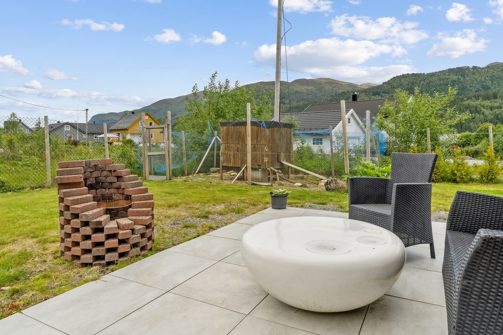 Terrassen strekker seg rundt tre sider av boligen, samt det er opparbeidet med belegningsstein ved garasjen Galleribilde