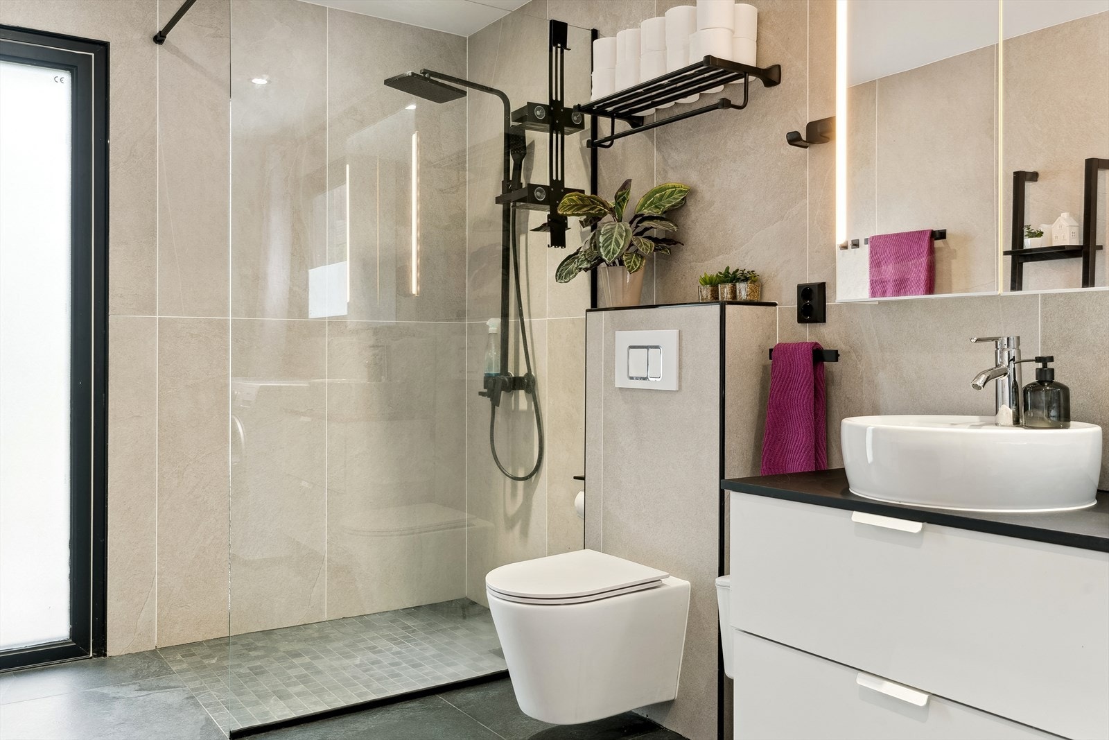 Stort baderom med dusjnisje, vegghengt wc, servant med innredning og speil Galleribilde