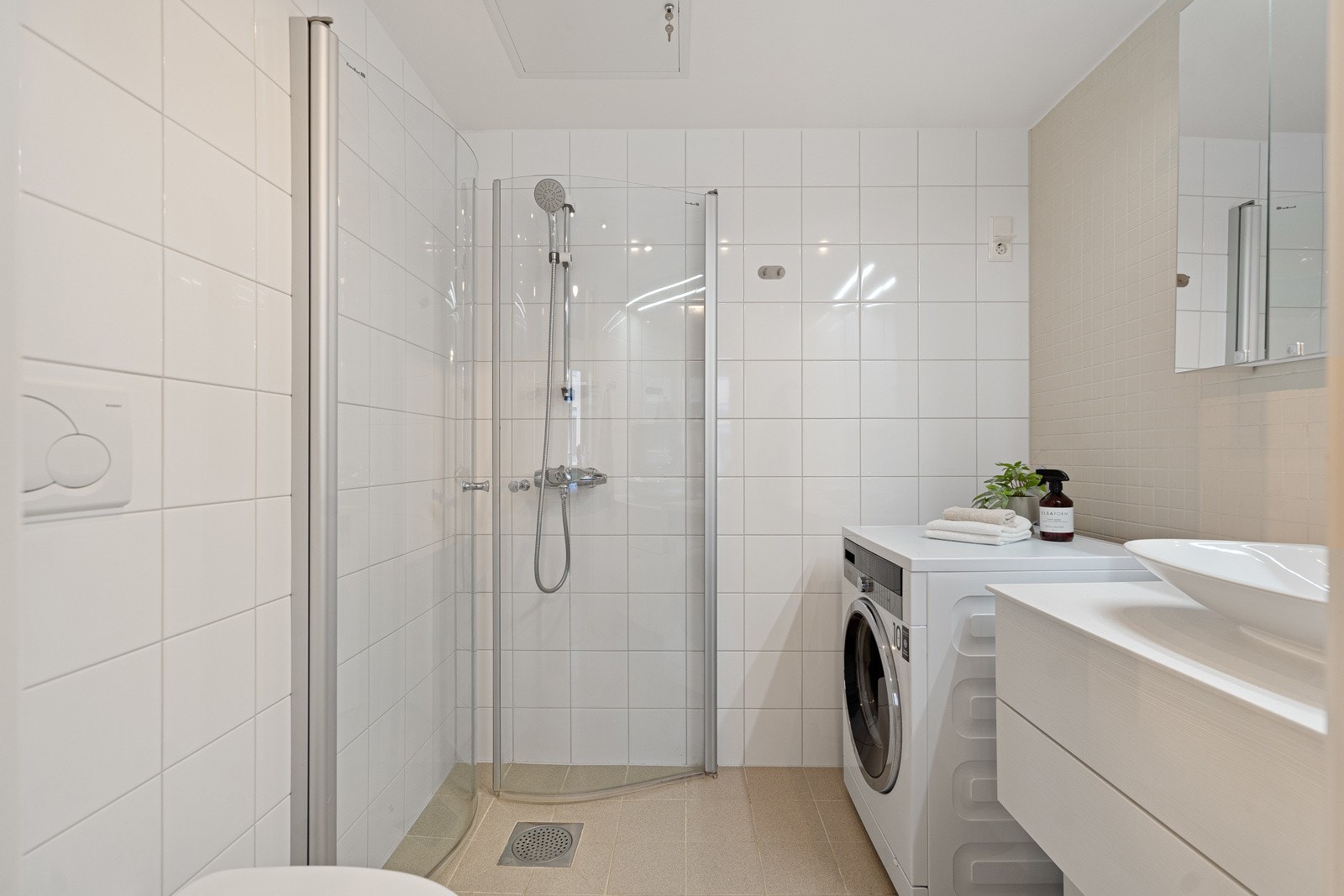 Badet er flislagt med gulvvarme og er innredet med dusjhjørne, vegghengt toalett, servant og opplegg for vaskemaskin. Galleribilde